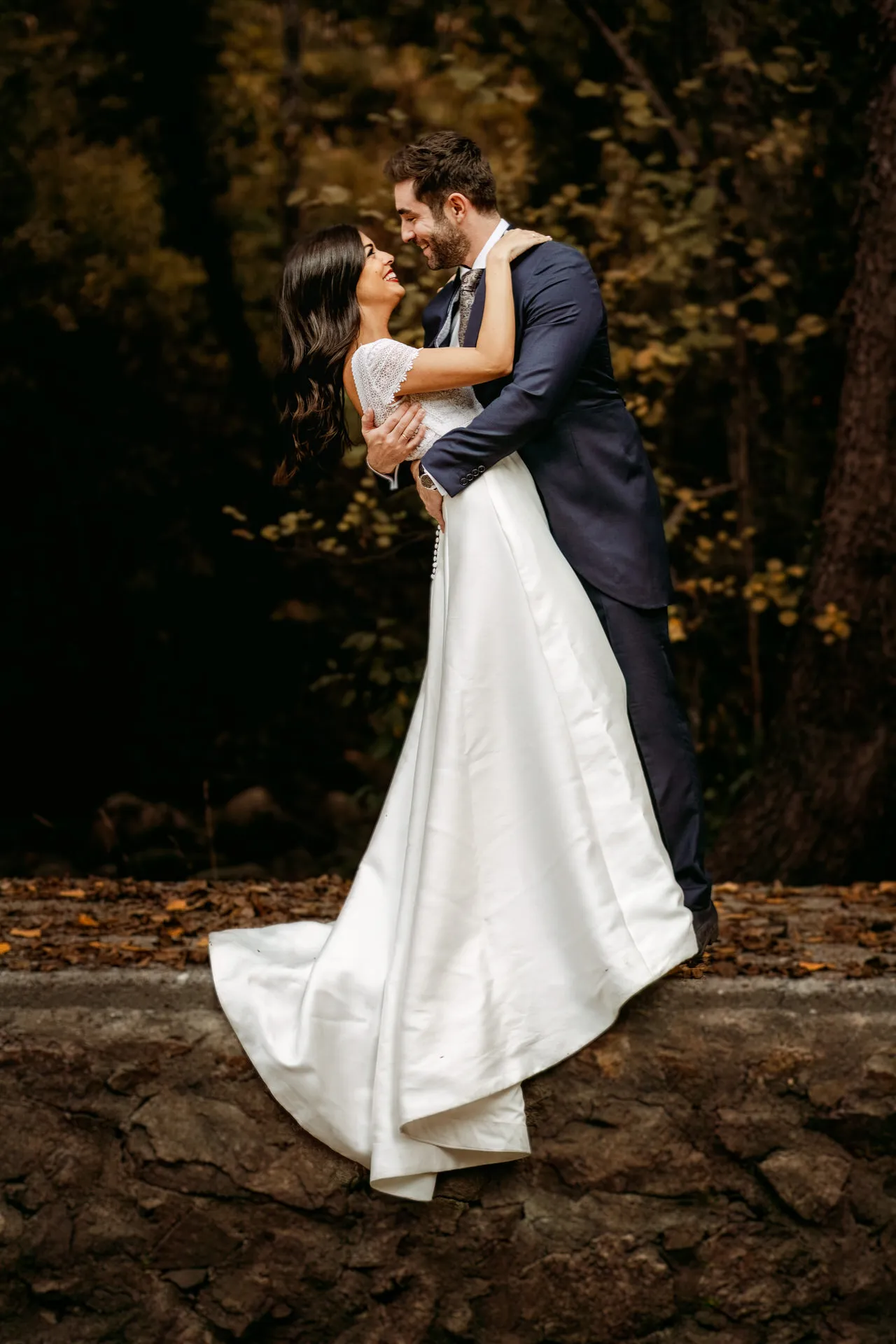 El novio abraza a la novia en un bosque otoñal