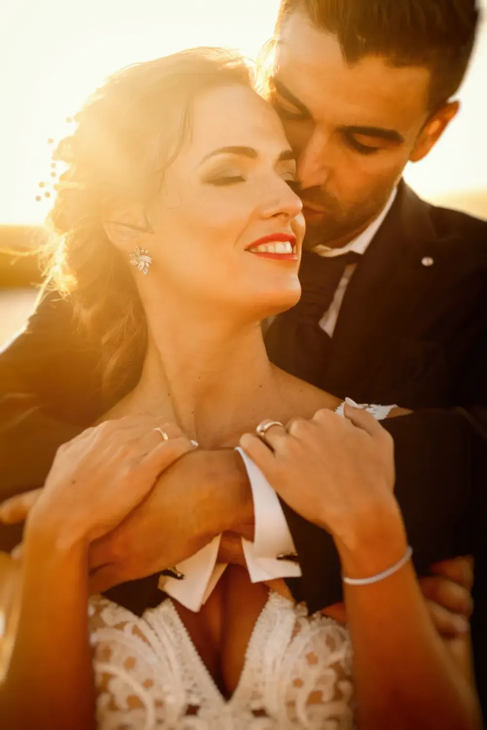 El novio abraza a la novia por la espalda a contraluz