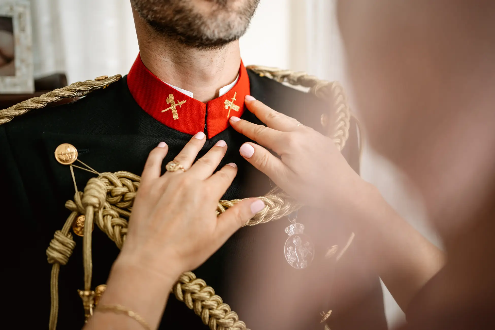 Una mano abrocha el cuello del uniforme de gala del novio, en Mérida
