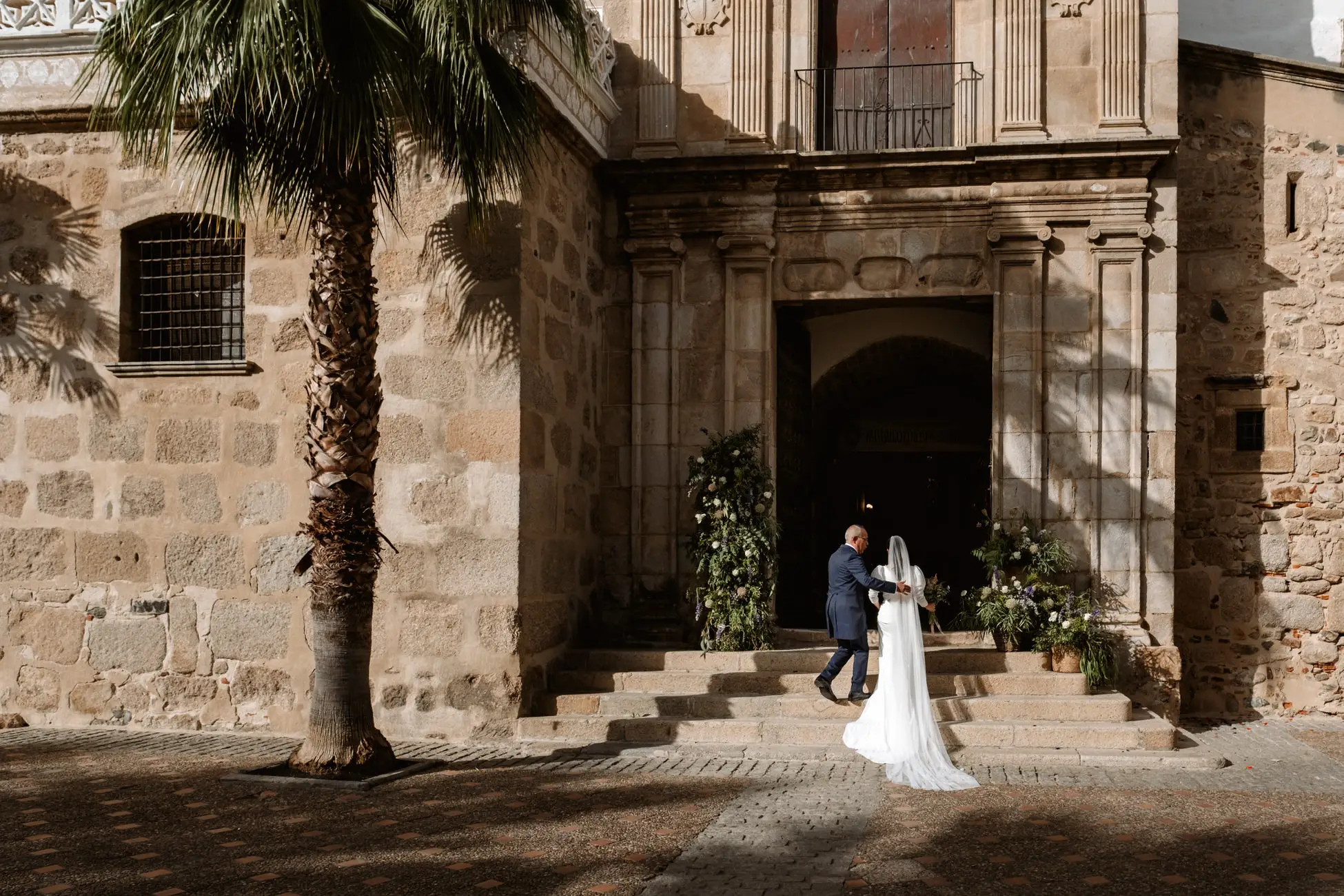 La novia sube la escalinata de la iglesia entre palmeras, en Mérida