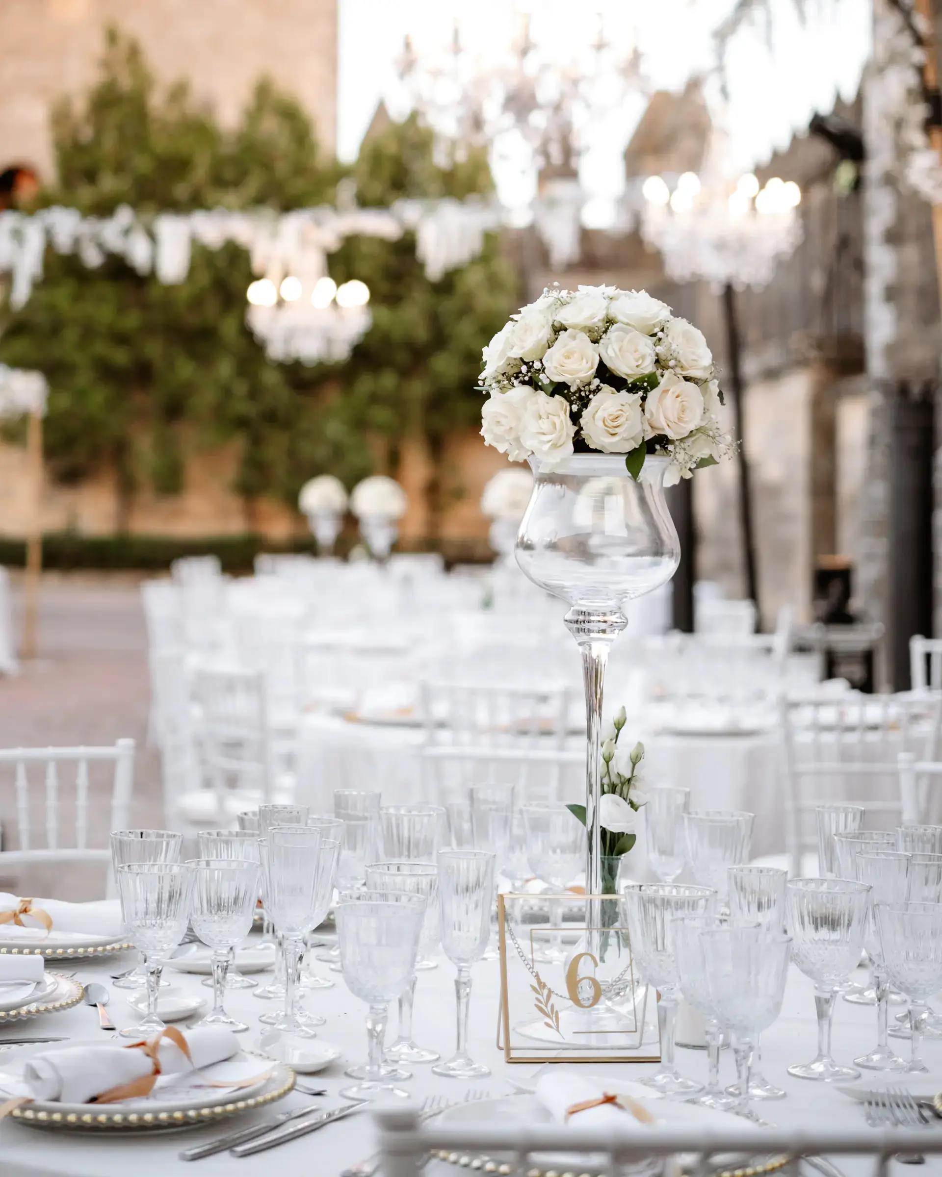 Mesas del banquete con rosas blancas y lámparas de cristal en un castillo