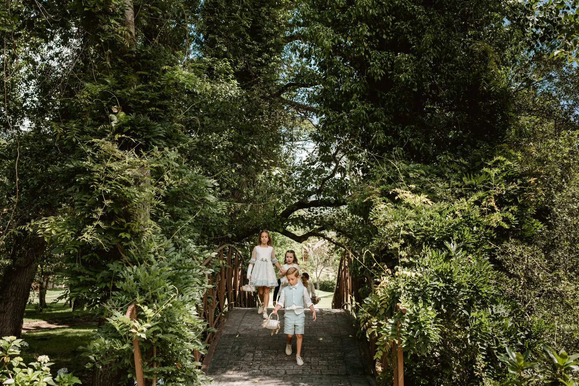 Los niños de arras cruzan un puente del jardín, en el Valle del Jerte (Cáceres)