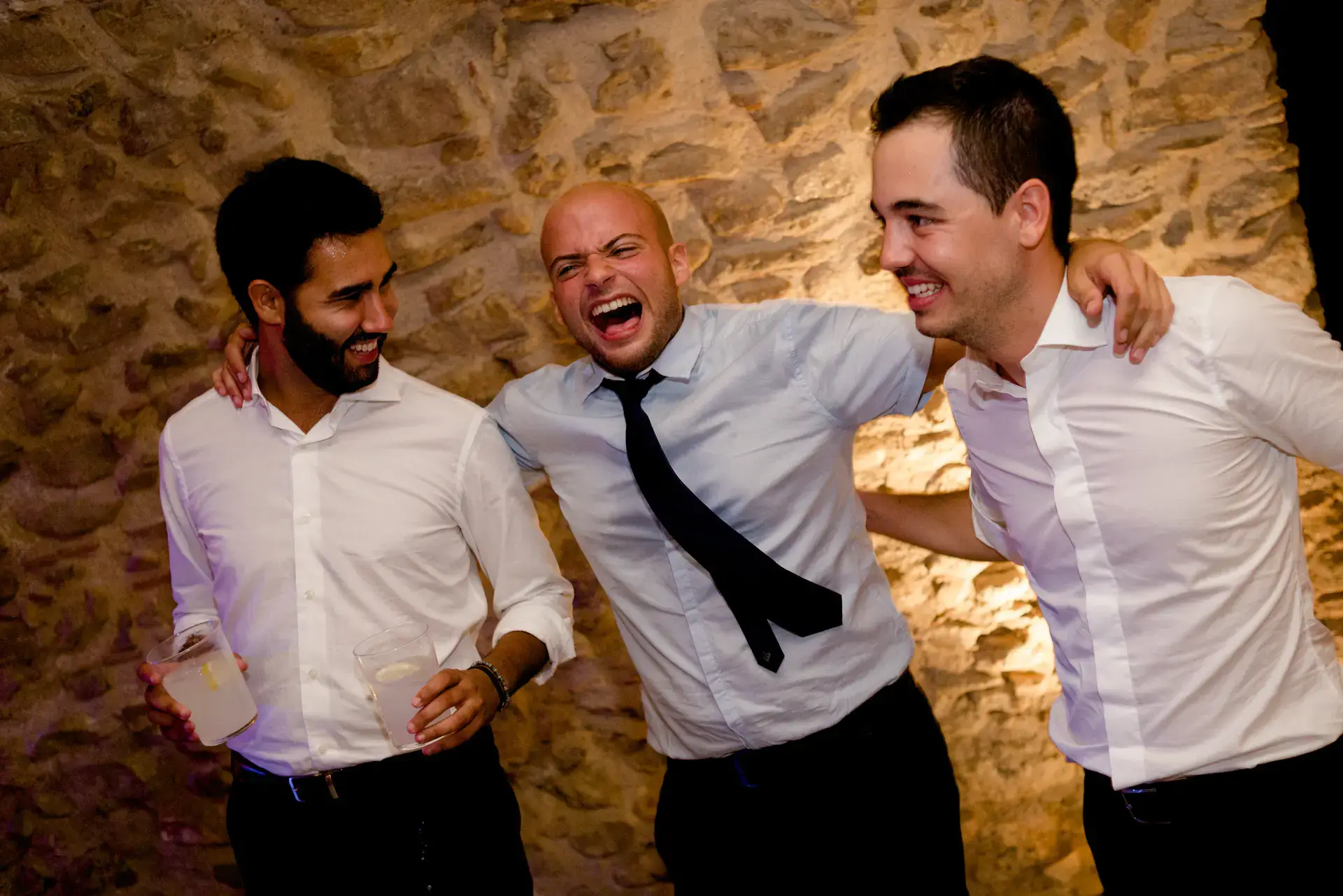 Tres amigos ríen abrazados en la fiesta, en el Castell d'Empordà, Girona