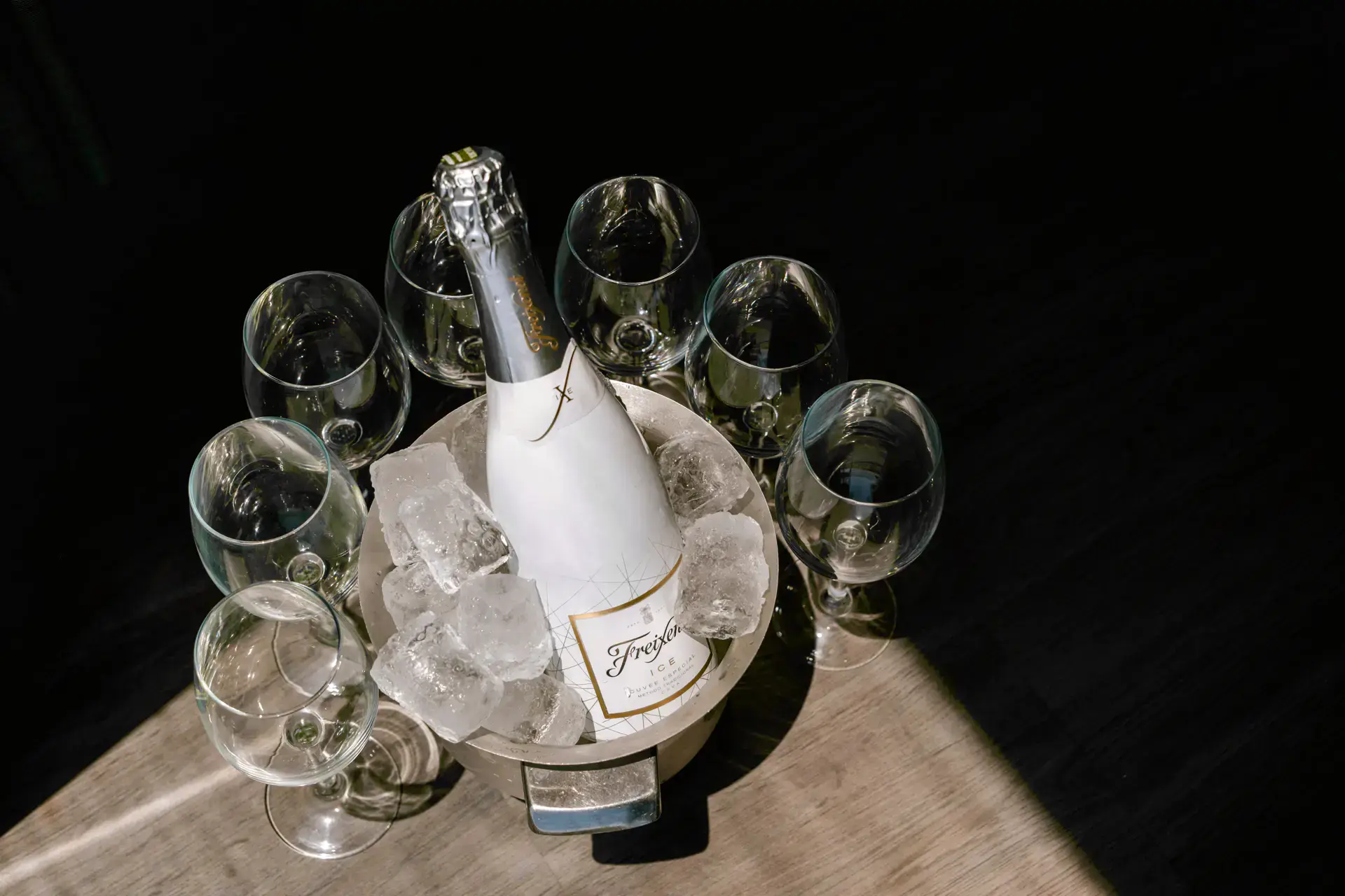Botella de cava en una cubitera rodeada de copas, en Córdoba
