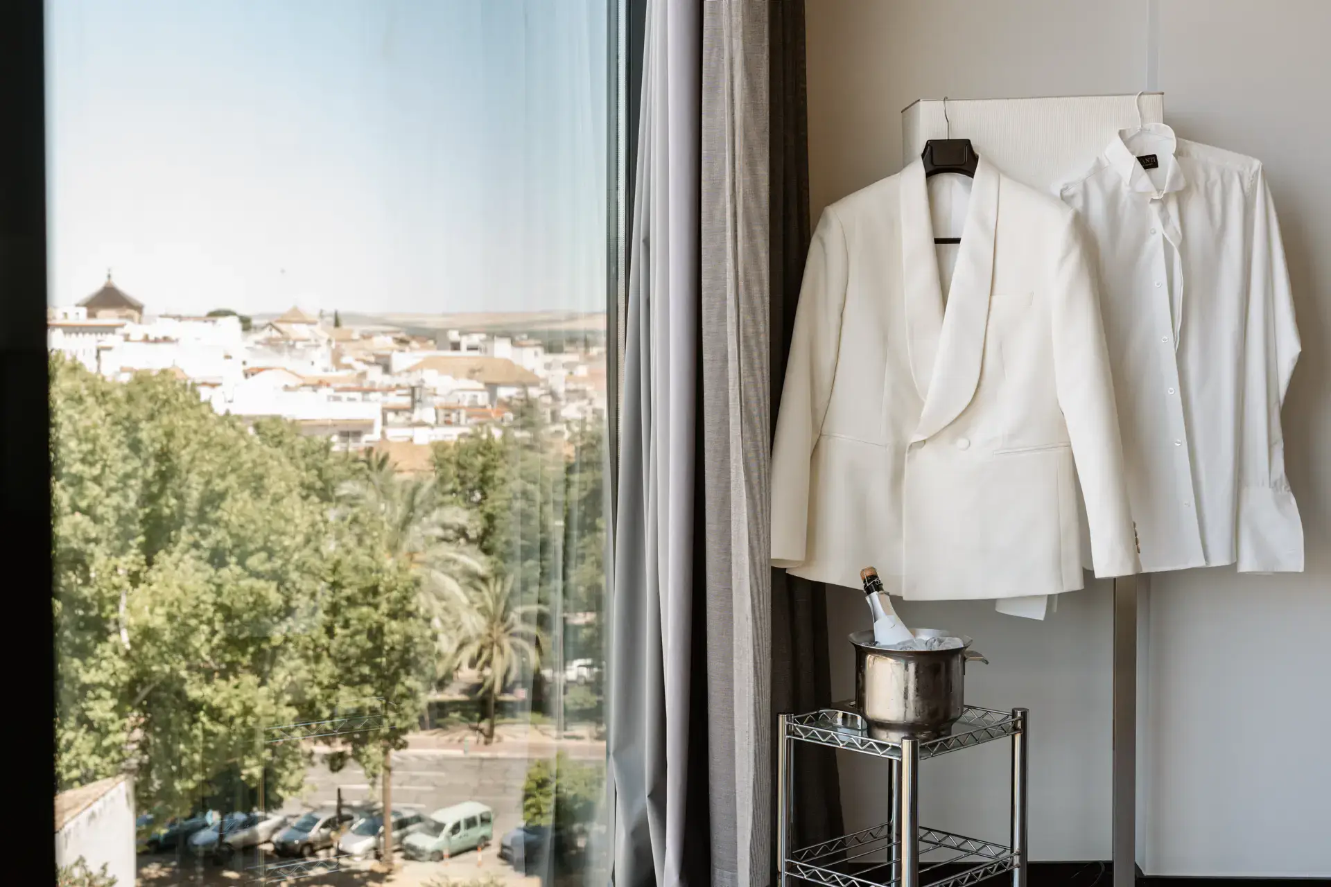 Esmoquin blanco del novio colgado junto a la ventana con vistas a Córdoba