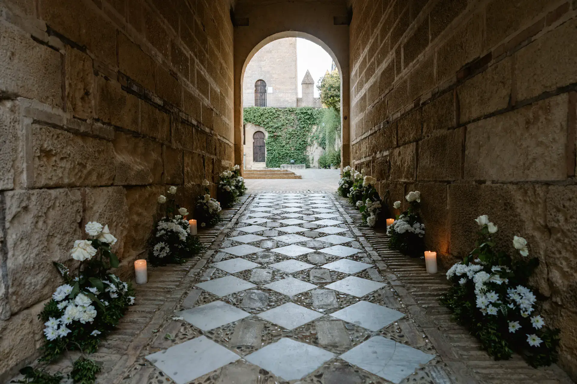 Pasillo de piedra decorado con flores y velas en el Castillo de Almodóvar