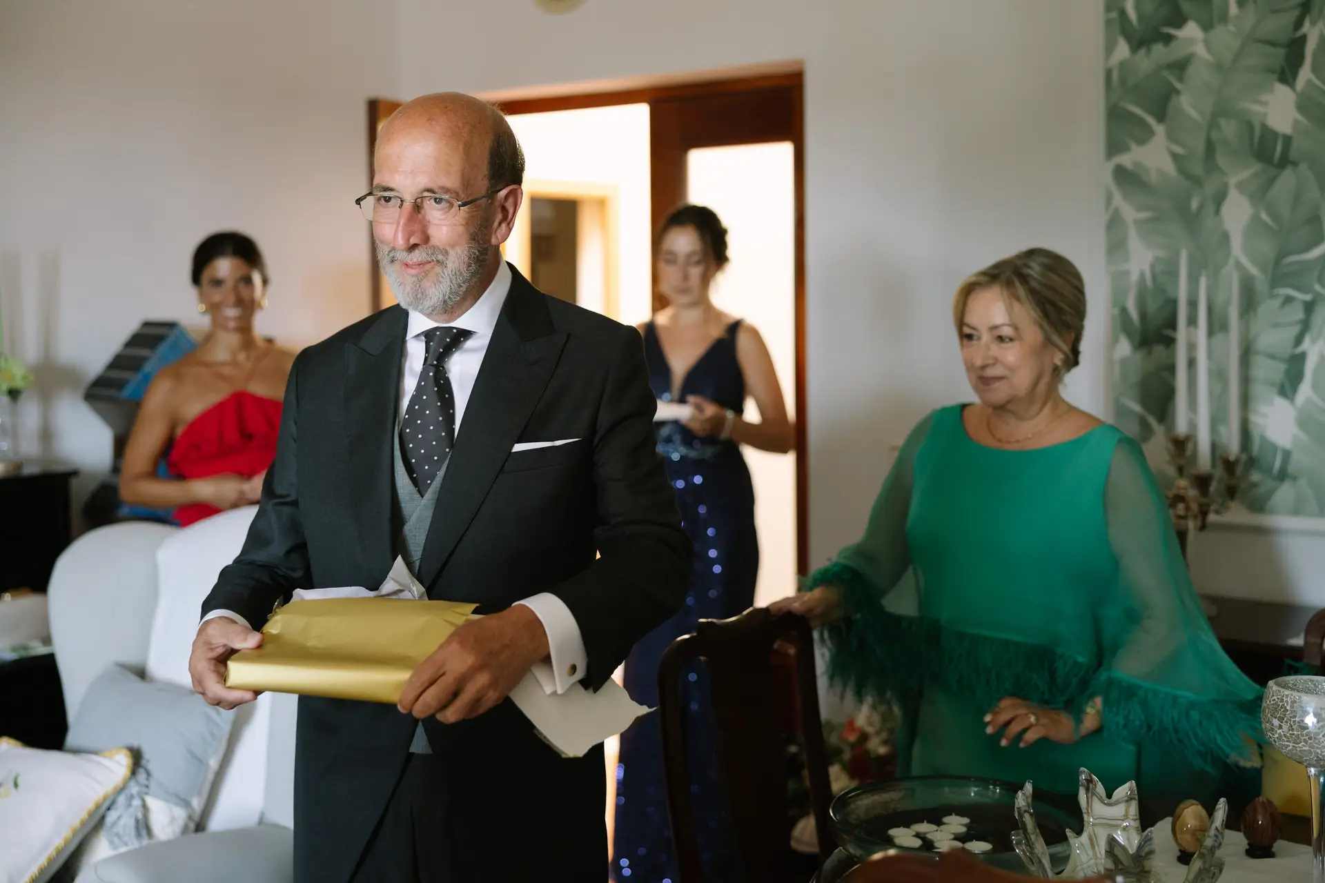 Un familiar con un regalo envuelto en dorado en el salón, en Jerez de los Caballeros