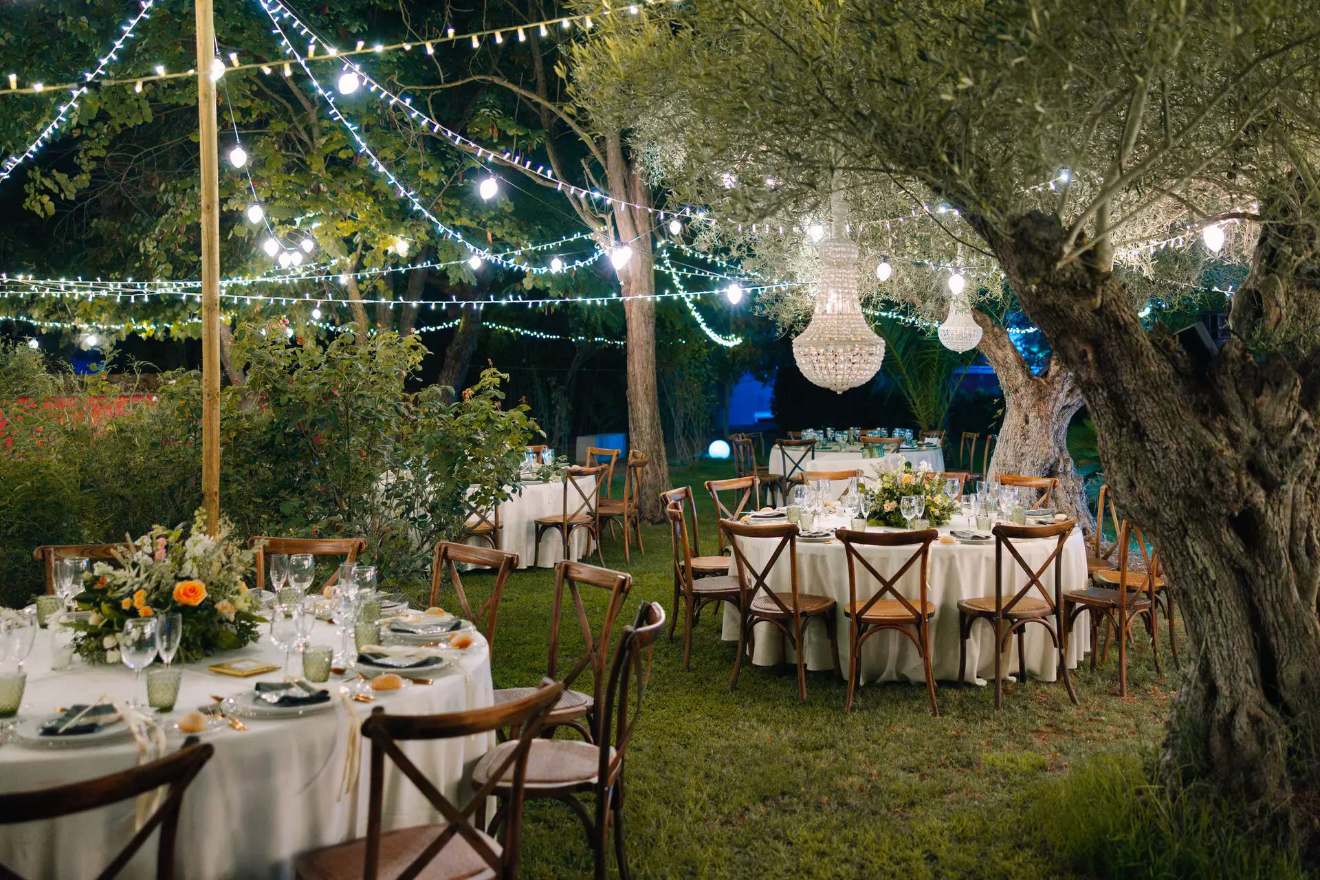 Mesas del banquete bajo un olivo iluminado en el Castillo de Toriñuelo