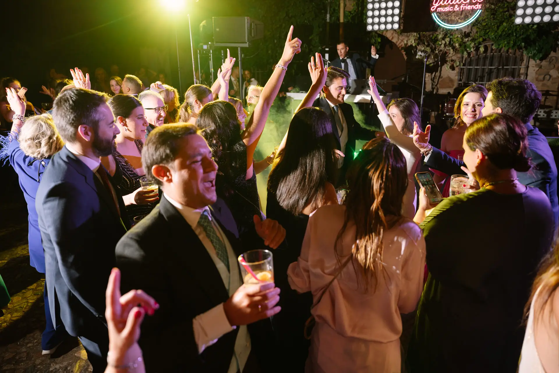 Invitados bailan con los brazos en alto frente al escenario, en Jerez de los Caballeros