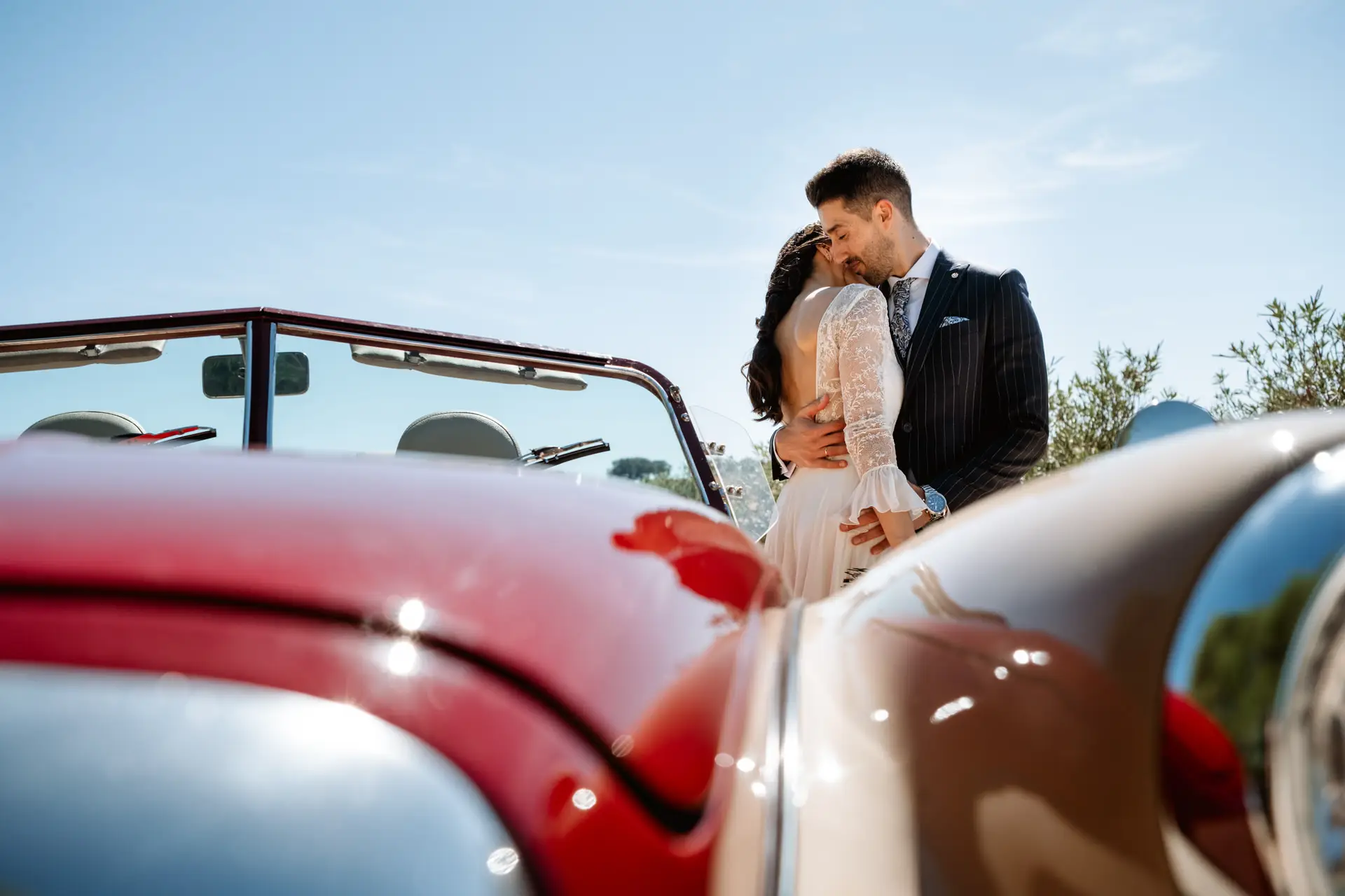 Los novios se besan junto al descapotable rojo, en Mérida