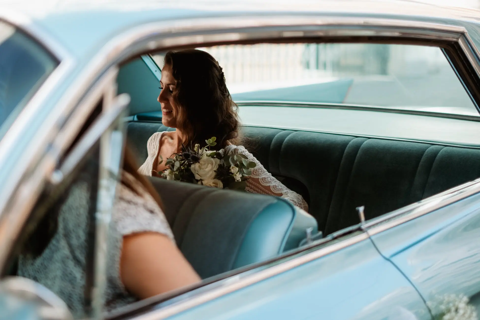 La novia mira por la ventanilla del coche clásico azul