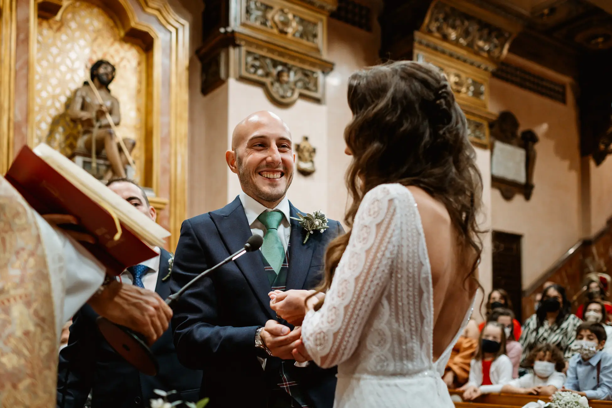El novio sonríe mientras pone el anillo a la novia en el altar