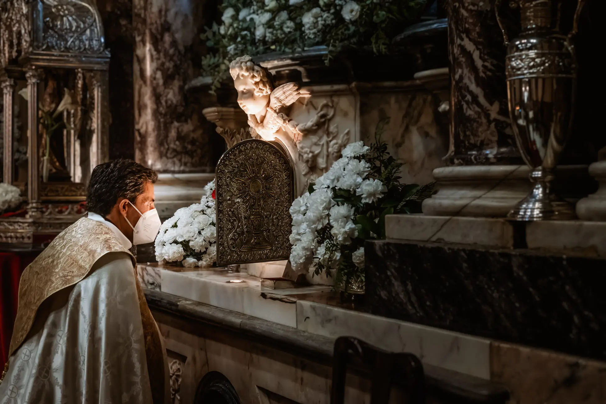 El sacerdote ante el altar con flores blancas