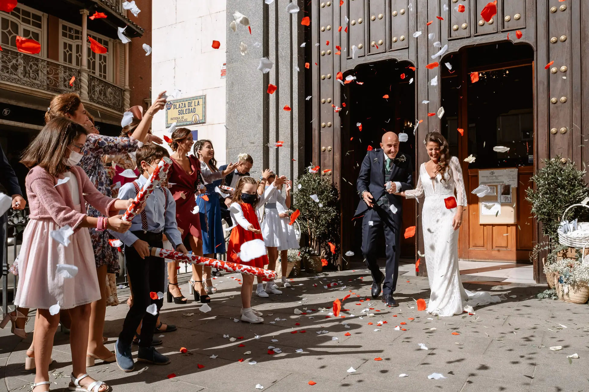 Los novios salen de la iglesia entre pétalos rojos