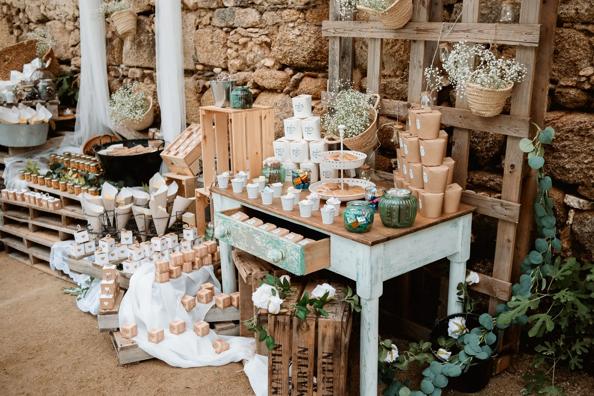 Mesa dulce con cajas de madera y flores, en el Lavadero de Lanas (Mérida)