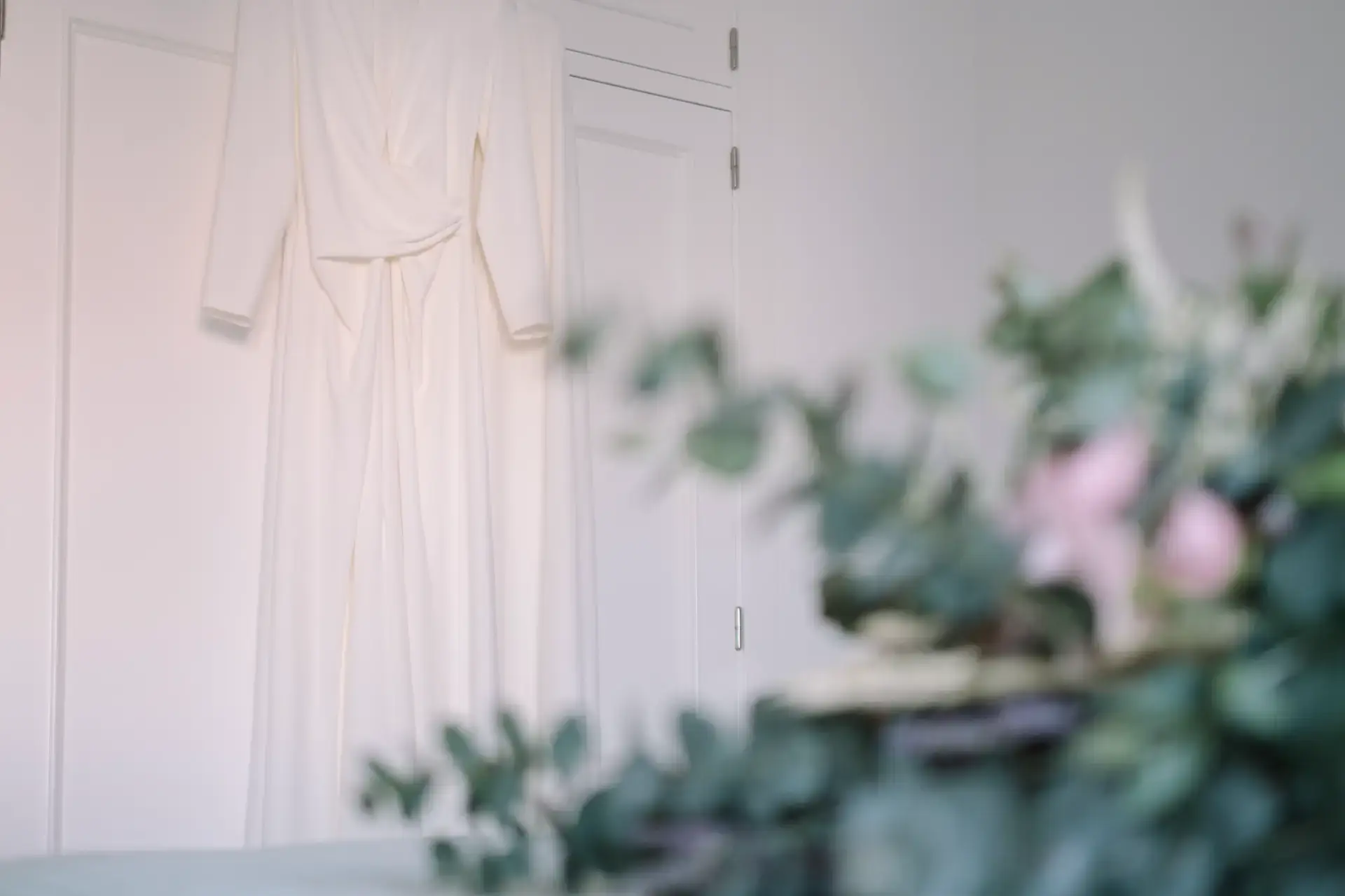 Vestido de novia colgado junto a flores rosas, en Badajoz