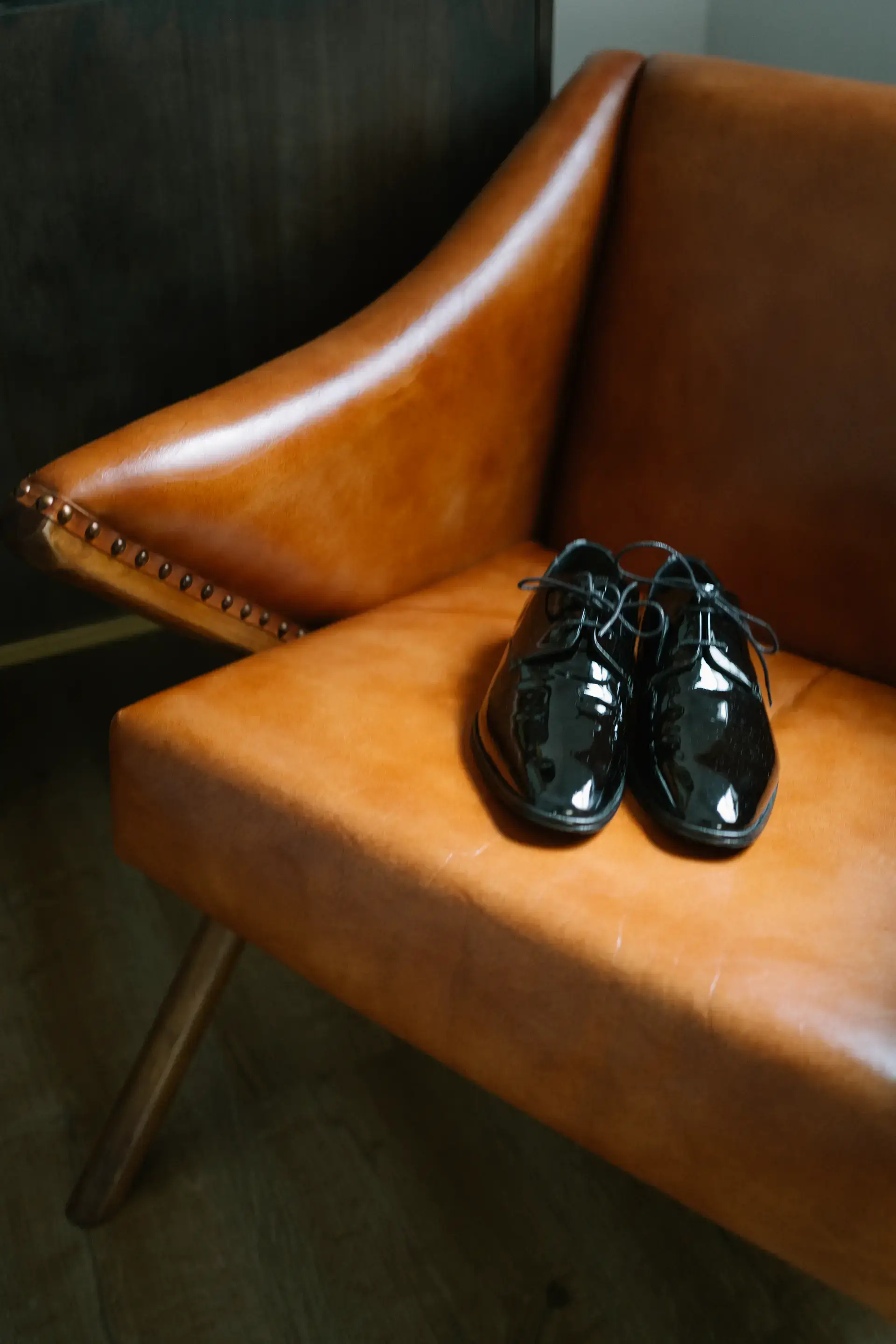 Zapatos de charol del novio sobre un sillón de cuero, en Badajoz