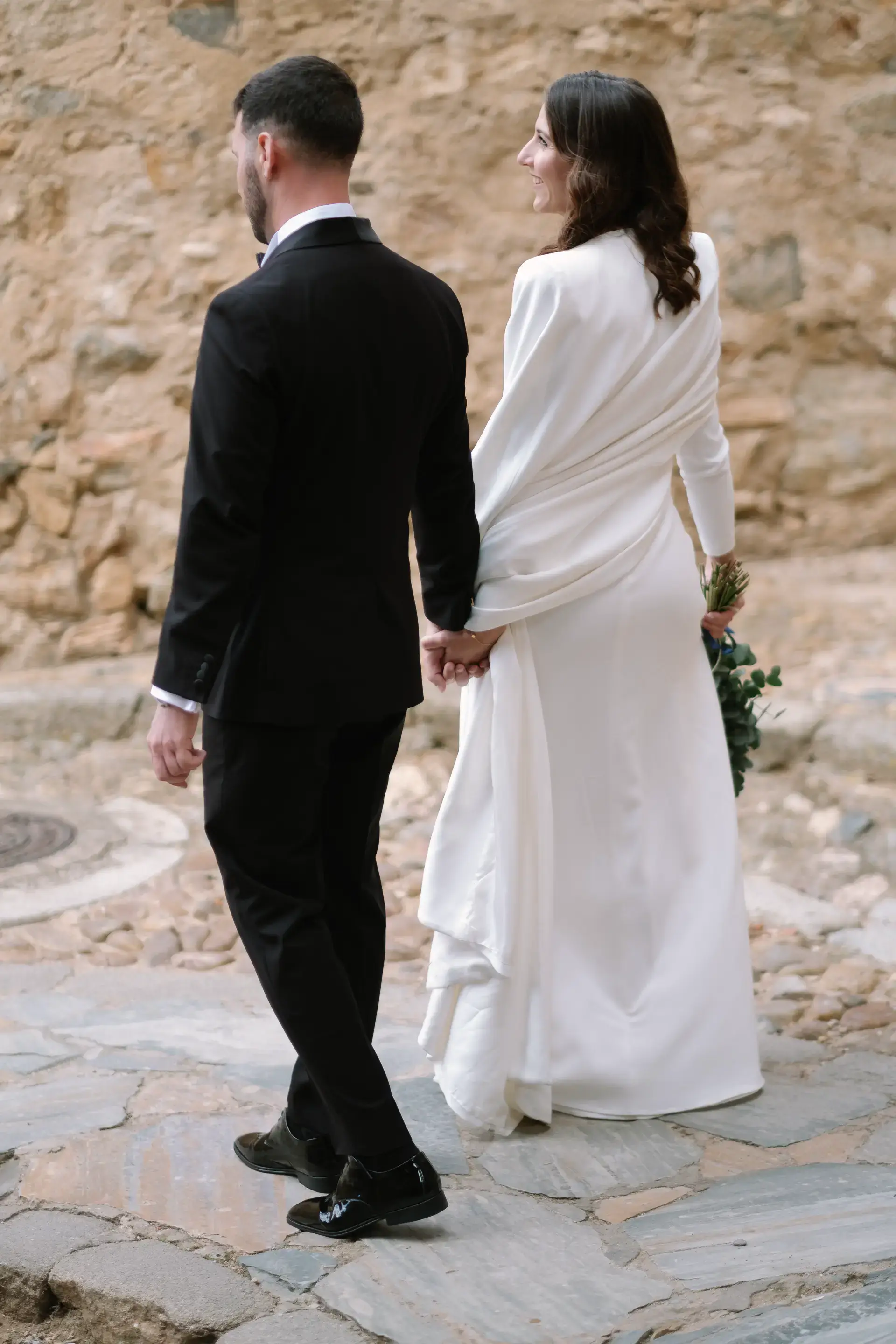 Ana y Jorge pasean de espaldas por un camino empedrado, en Badajoz