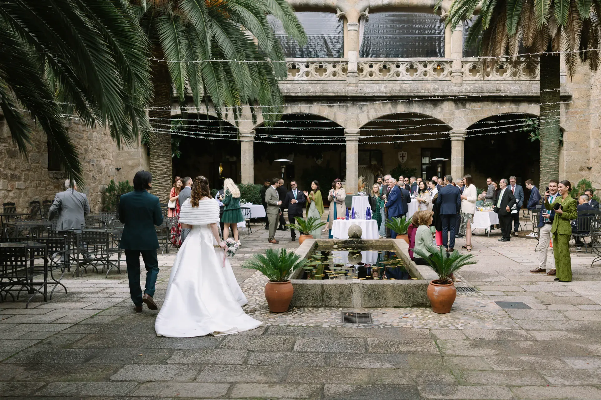 Gemma y Russell de espaldas ante el patio porticado lleno de invitados