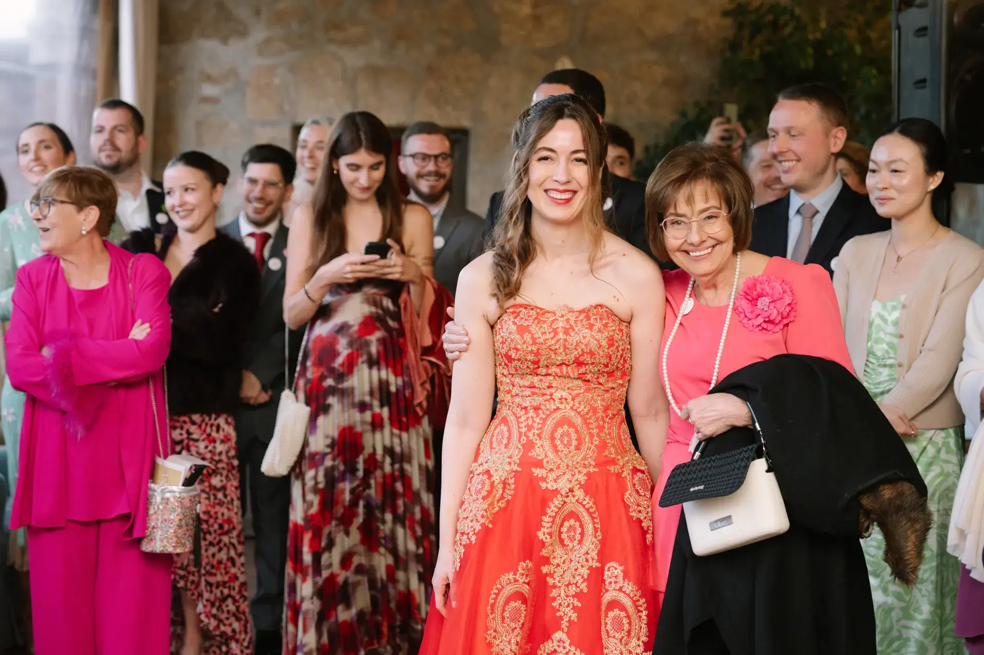 Gemma con su vestido rojo y sus invitadas escuchan los discursos, en el Parador de Jarandilla