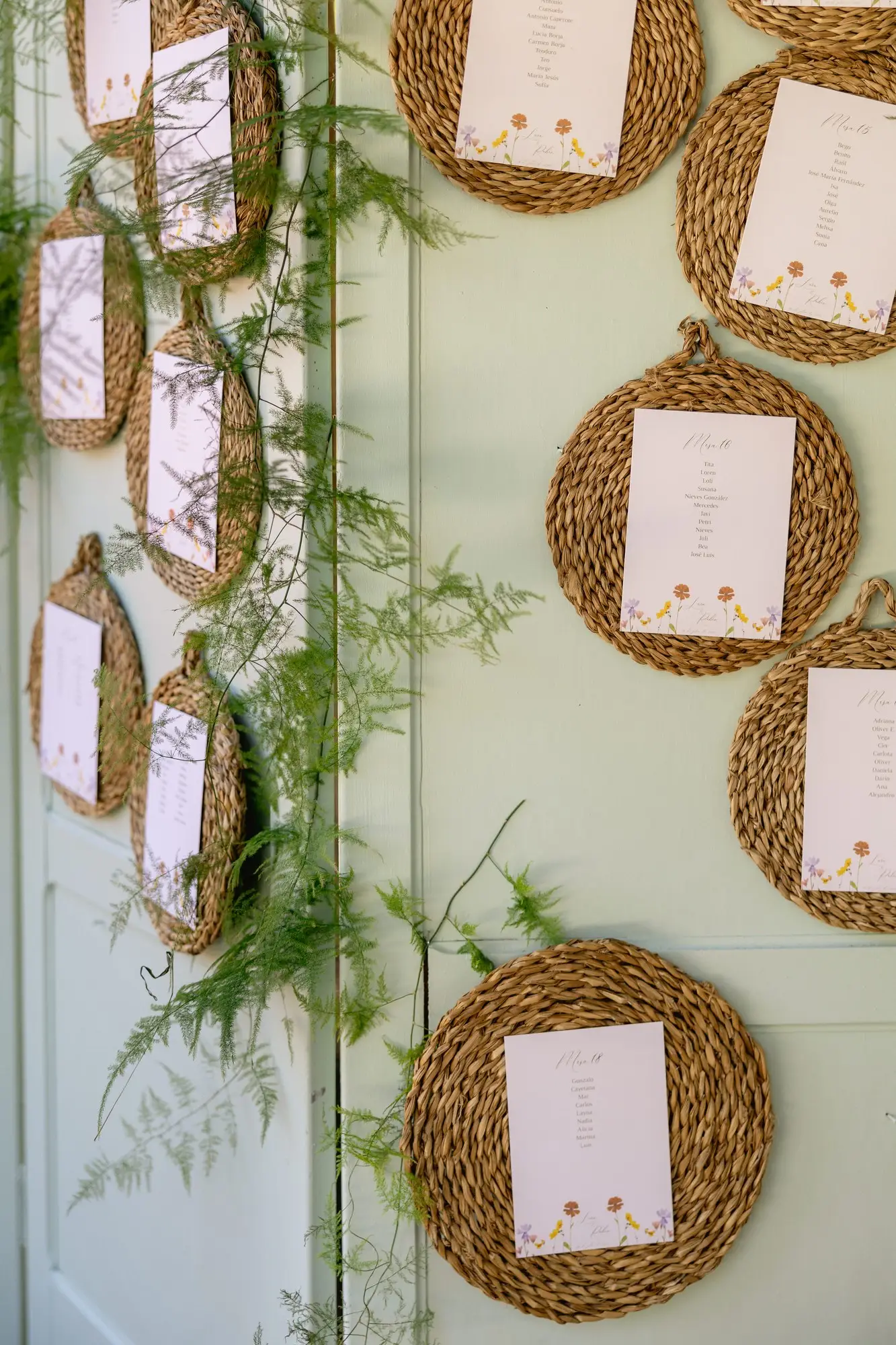 Seating de la boda con platos de esparto y tarjetas colgados en una pared, en el Hotel Ruta Imperial de Jarandilla