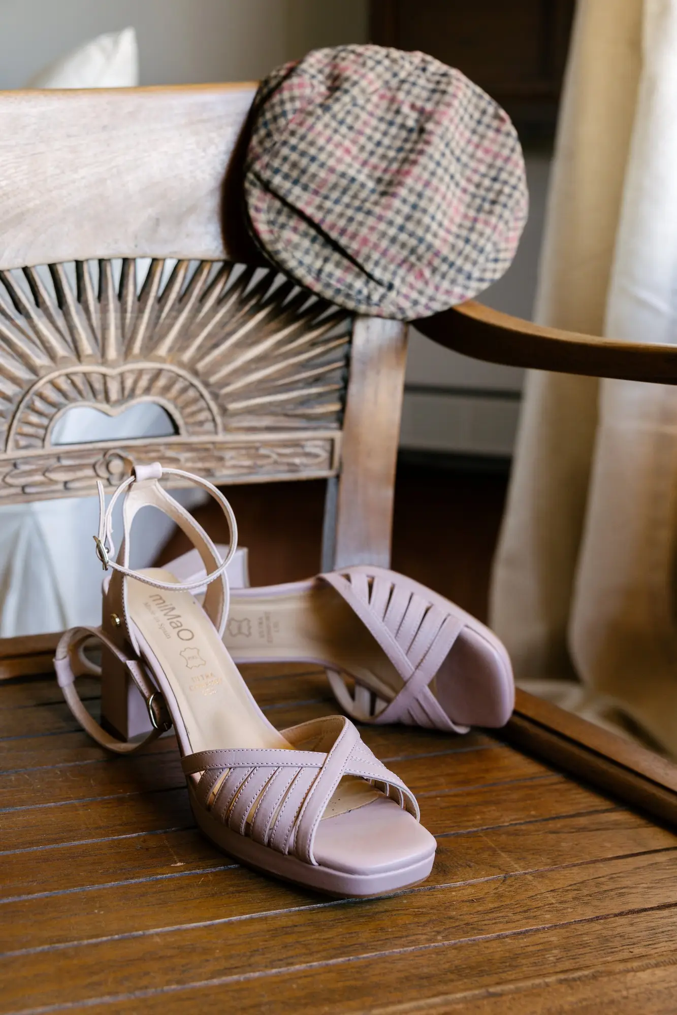Sandalias de novia y una gorra de cuadros sobre un sillón de madera, en el Hotel Ruta Imperial de Jarandilla