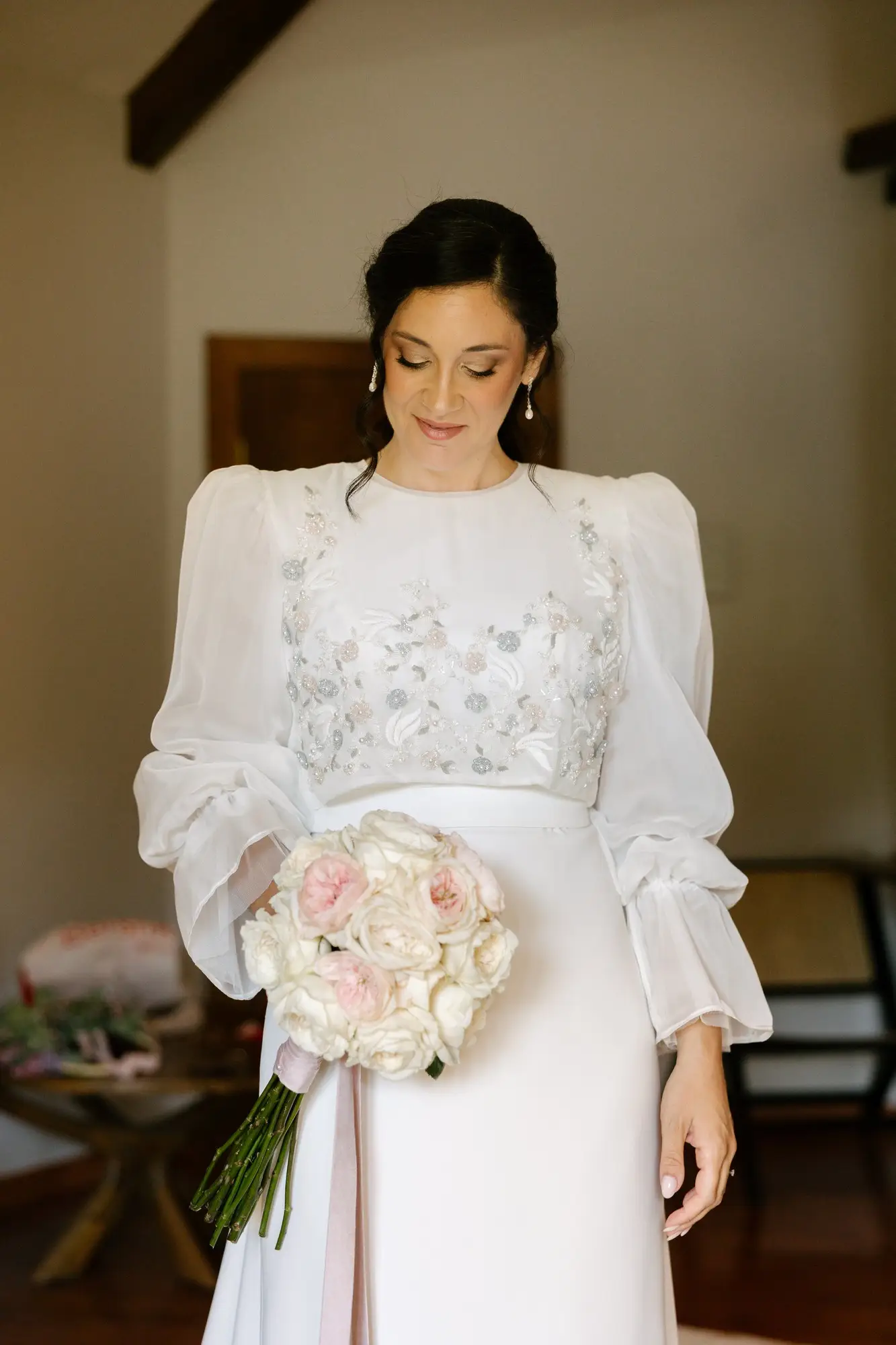 Lara, con el vestido de novia y el ramo, mira hacia abajo en la habitación, en el Hotel Ruta Imperial de Jarandilla