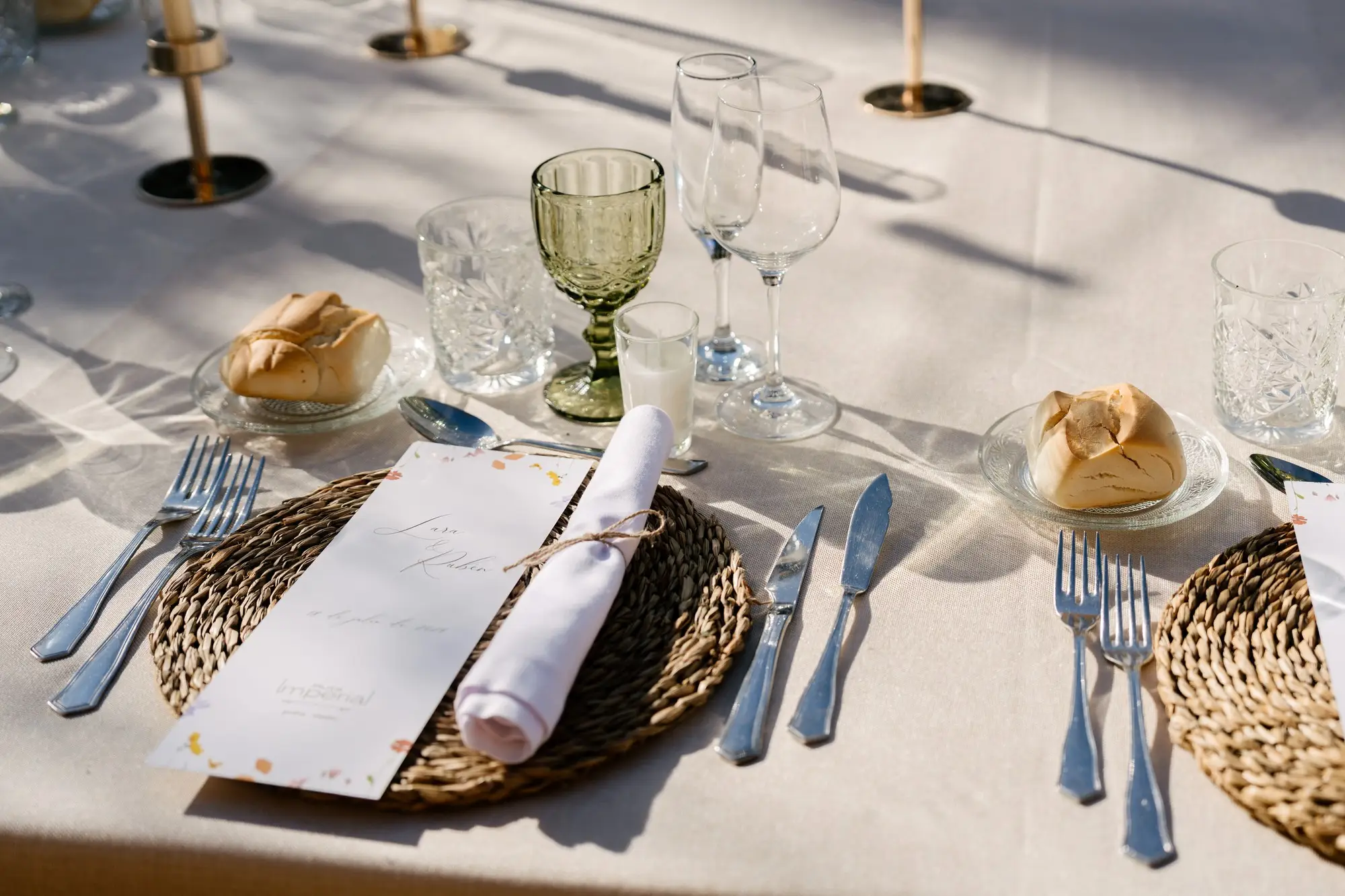 Mesa del banquete con bajoplato de esparto, menú y panecillo, en el Hotel Ruta Imperial de Jarandilla