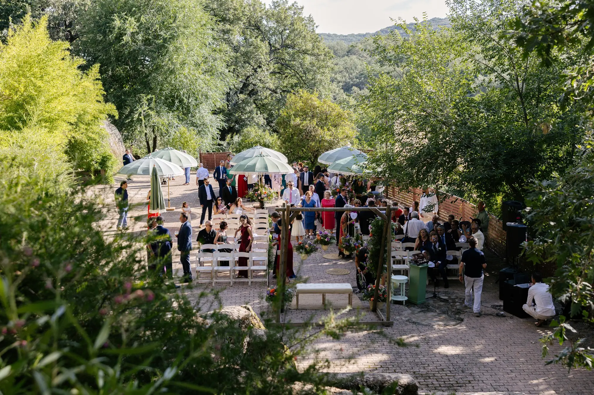 El jardín de la ceremonia visto desde arriba, con sombrillas e invitados, en el Hotel Ruta Imperial de Jarandilla