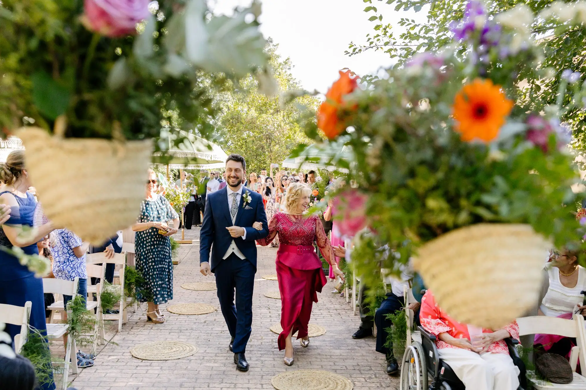 Rubén entra a la ceremonia del brazo de una familiar, entre cestas de flores, en el Hotel Ruta Imperial de Jarandilla