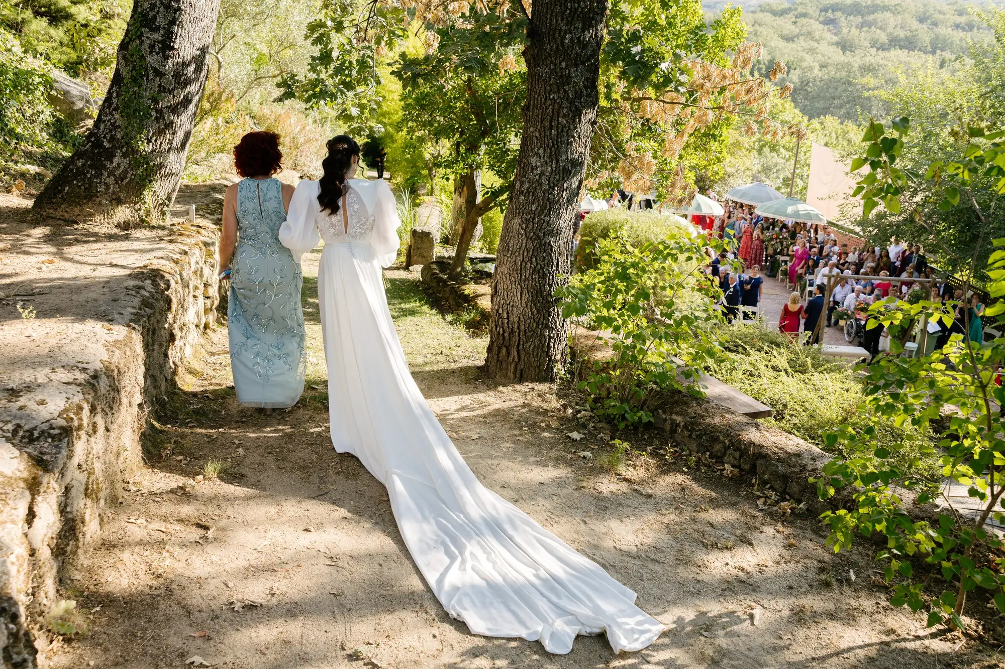 Lara, de espaldas y con la cola del vestido, baja con una familiar hacia la ceremonia, en el Hotel Ruta Imperial de Jarandilla