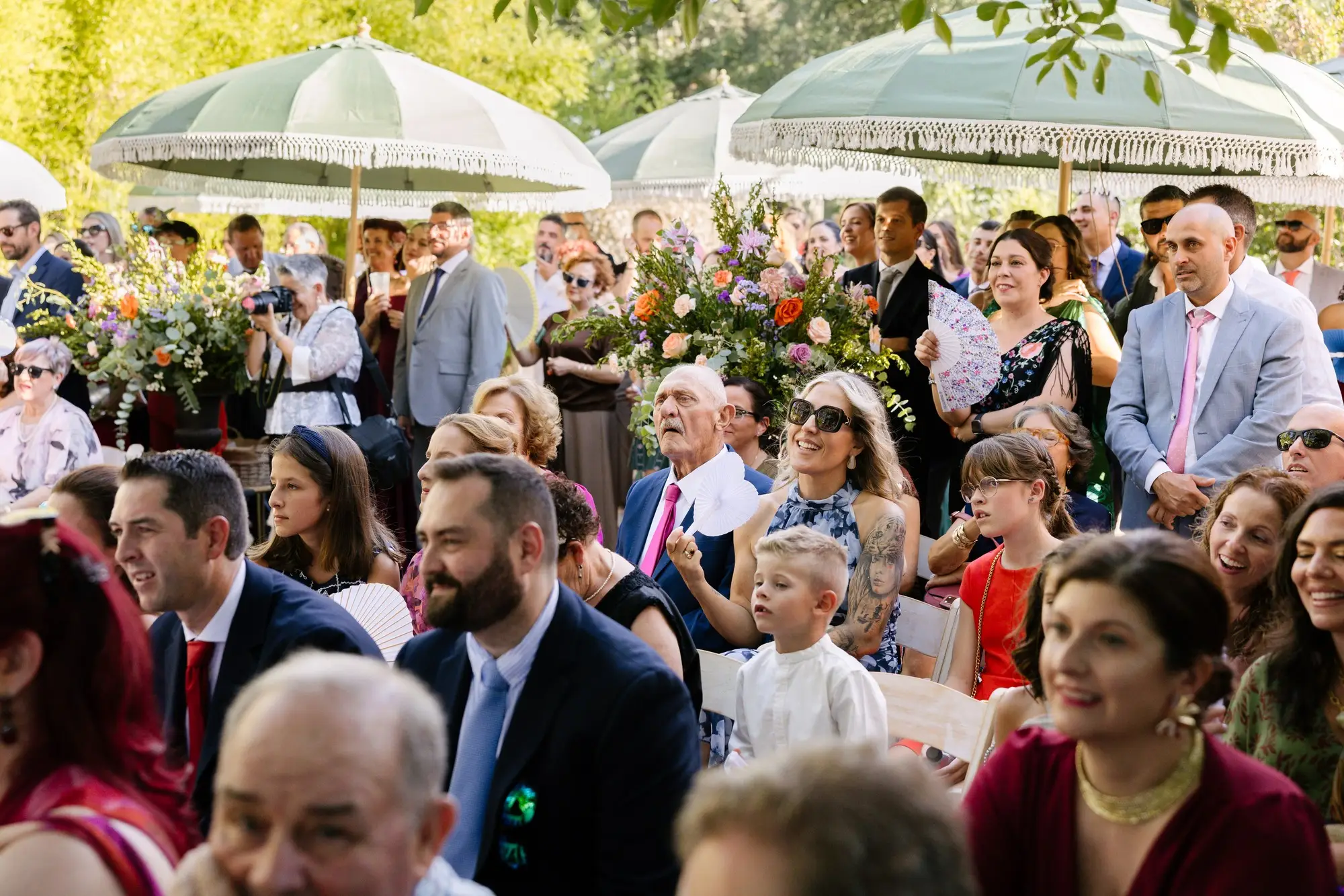 Invitados ríen bajo las sombrillas durante la ceremonia, en el Hotel Ruta Imperial de Jarandilla
