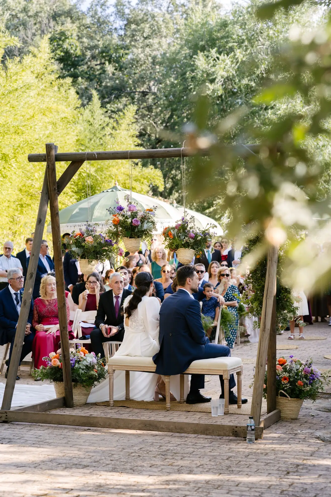 La pérgola de madera y los invitados, vistos desde lejos entre la vegetación, en el Hotel Ruta Imperial de Jarandilla