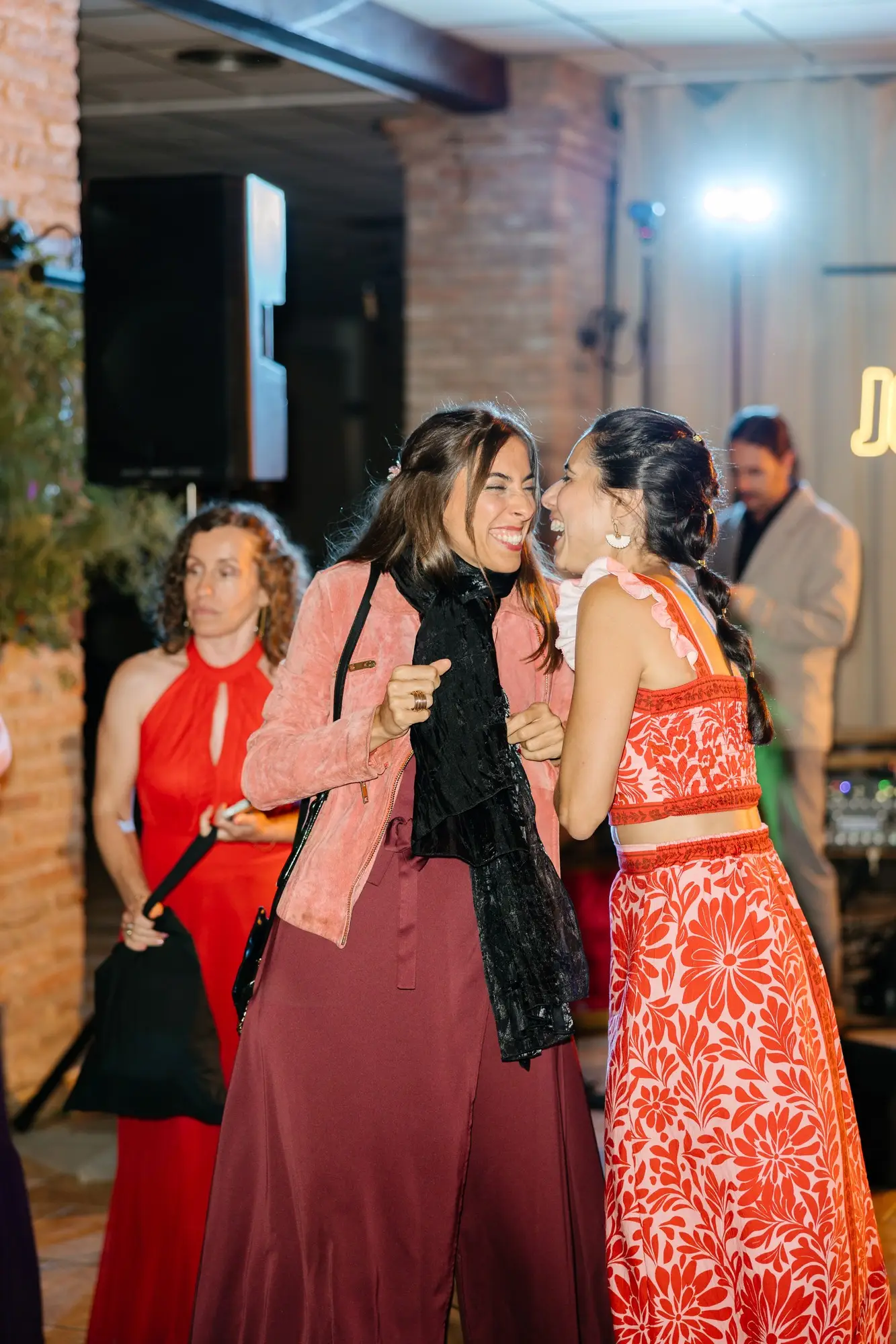 Dos invitadas de rojo se abrazan en el salón del hotel, en el Hotel Ruta Imperial de Jarandilla