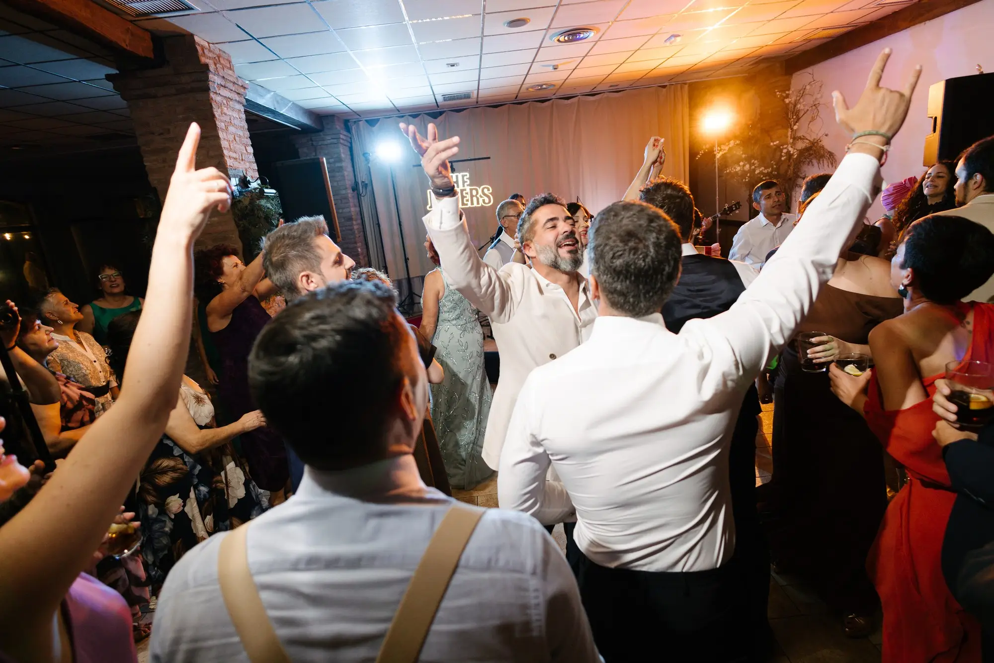 Invitados levantan los brazos en la pista de baile, en el Hotel Ruta Imperial de Jarandilla