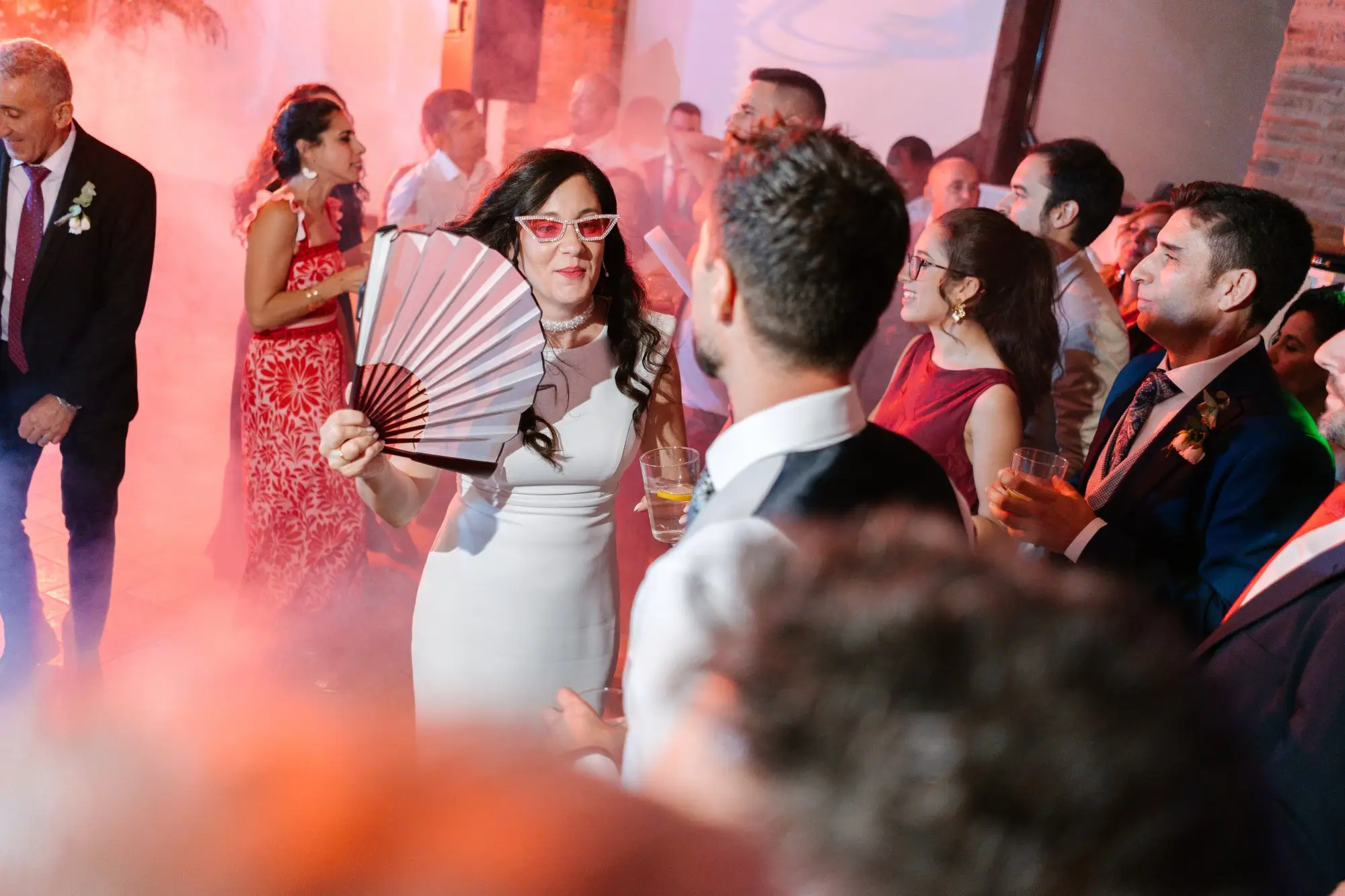 Lara, con gafas y abanico, entre humo rosa en la fiesta, en el Hotel Ruta Imperial de Jarandilla