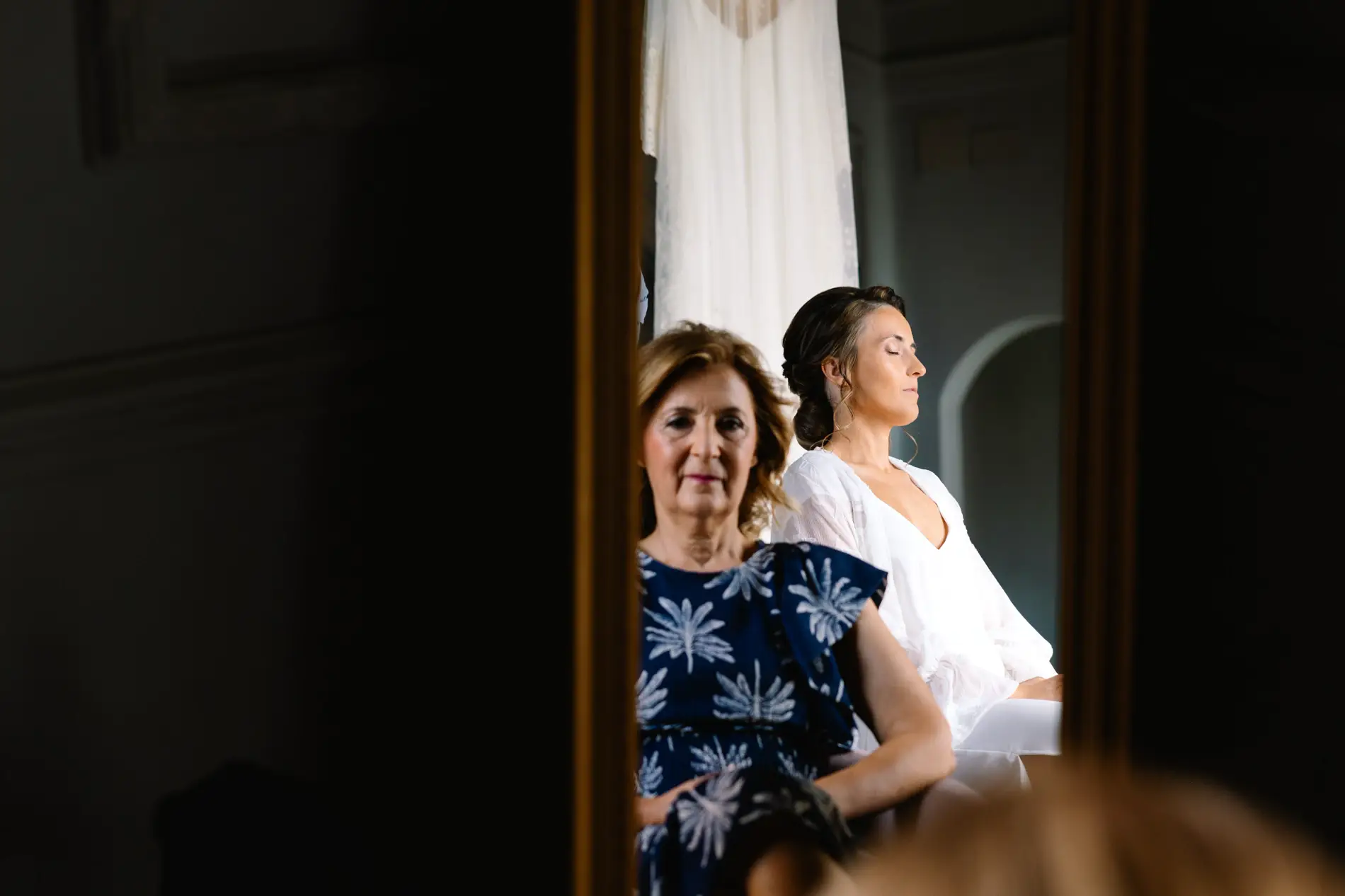 María se prepara junto a una familiar reflejadas en el espejo, en Casa Colorada, Badajoz