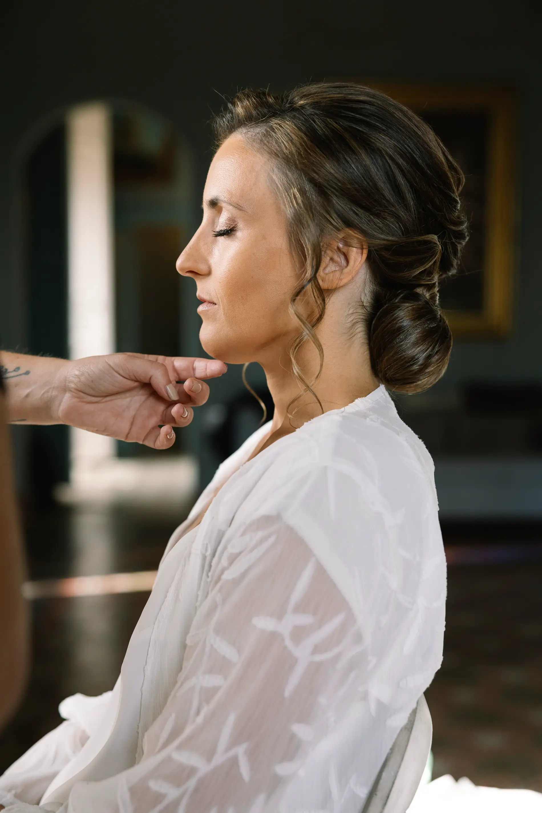 María, con los ojos cerrados, mientras le retocan el maquillaje, en Casa Colorada, Badajoz