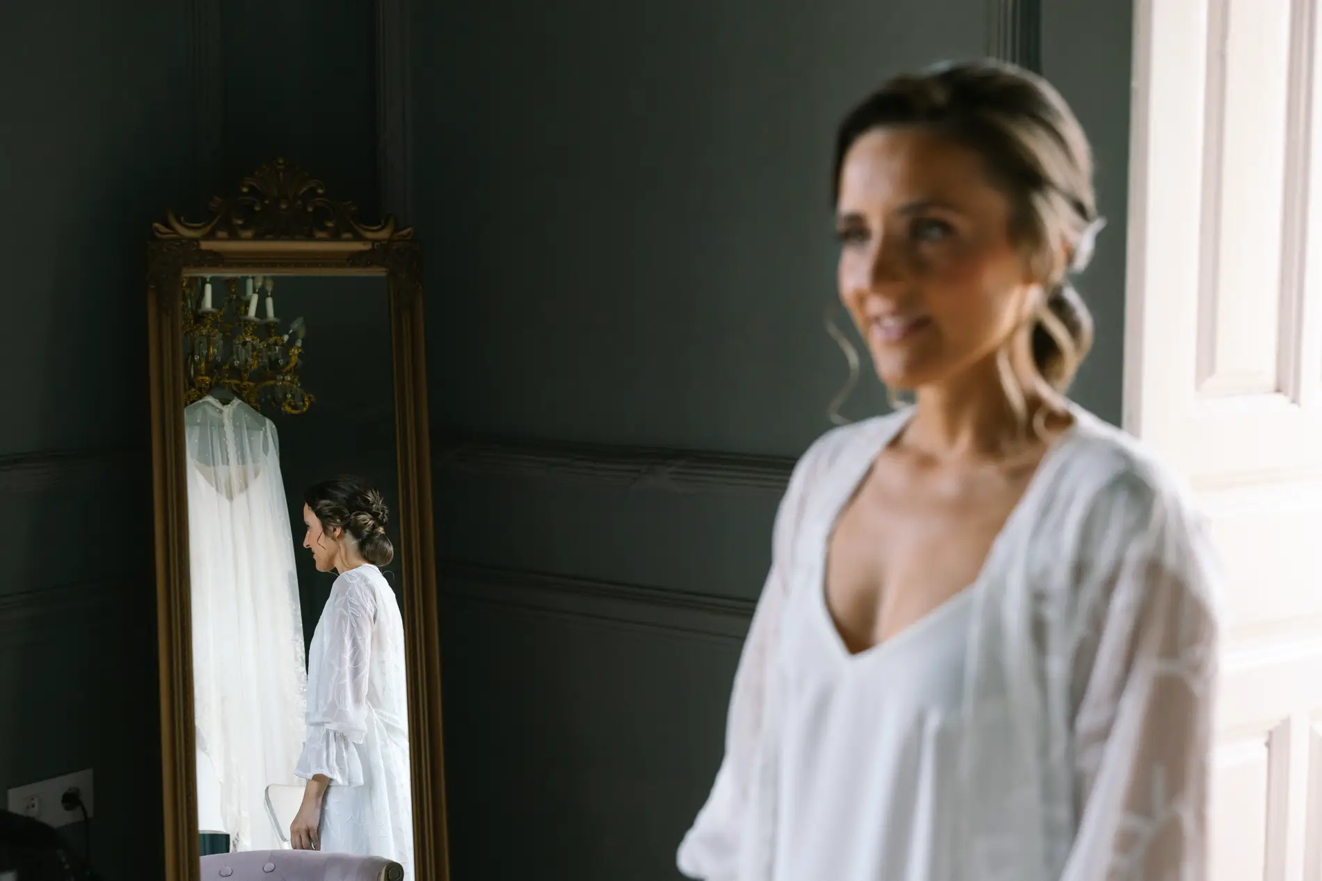 María sonríe junto a un espejo de pie durante los preparativos, en Casa Colorada, Badajoz