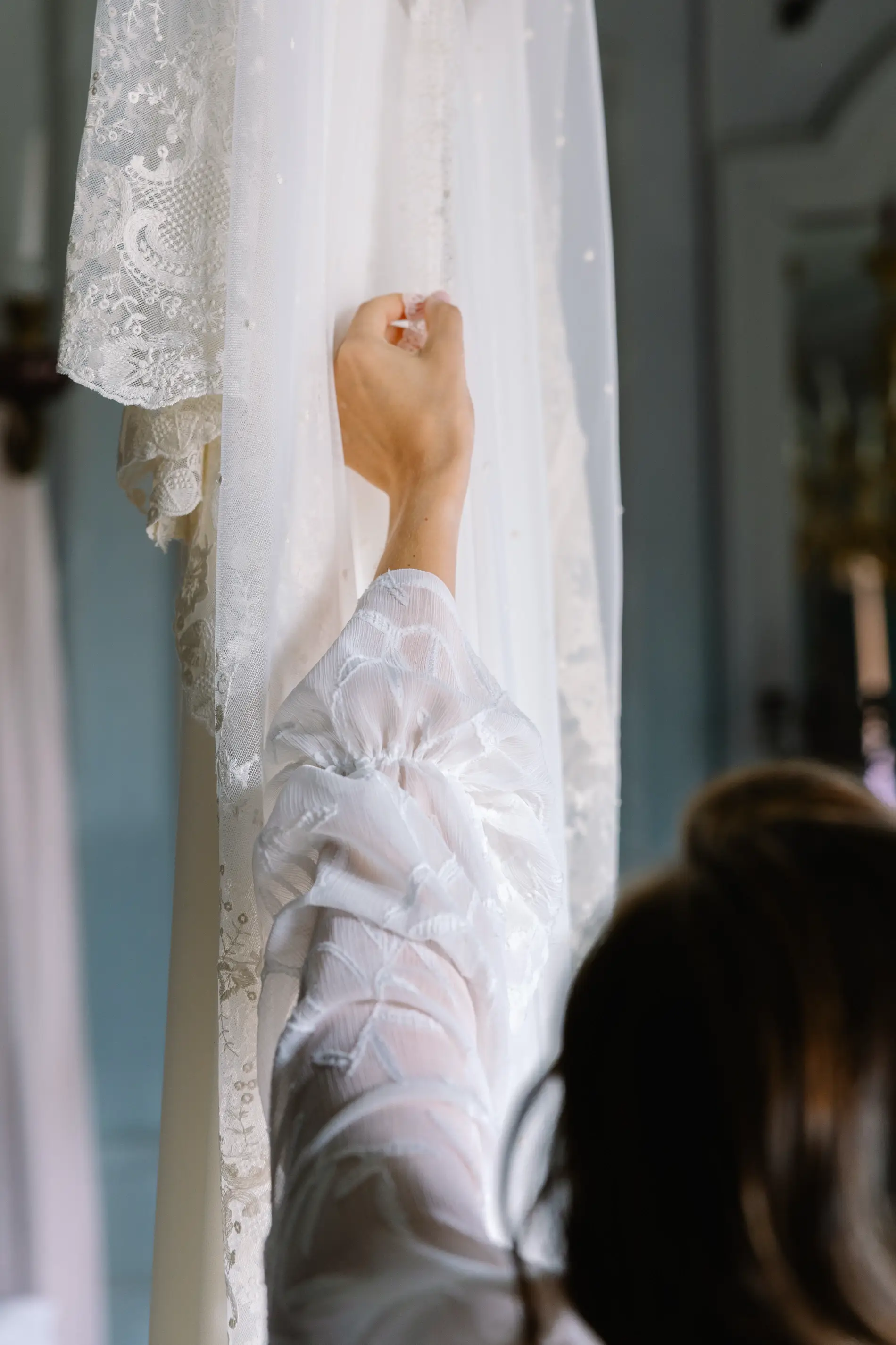 Detalle de la mano de María junto al vestido de novia colgado, en Casa Colorada, Badajoz