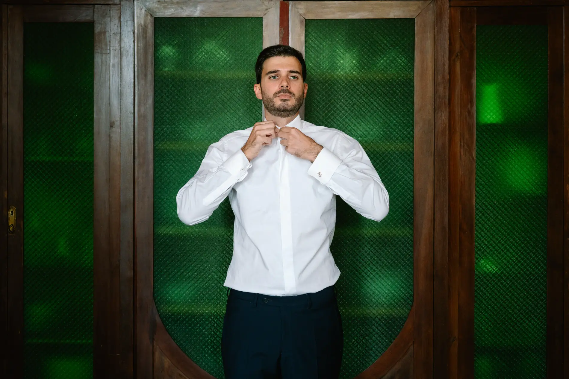 Álvaro se abrocha la camisa ante un armario de cristales verdes, en Casa Colorada, Badajoz