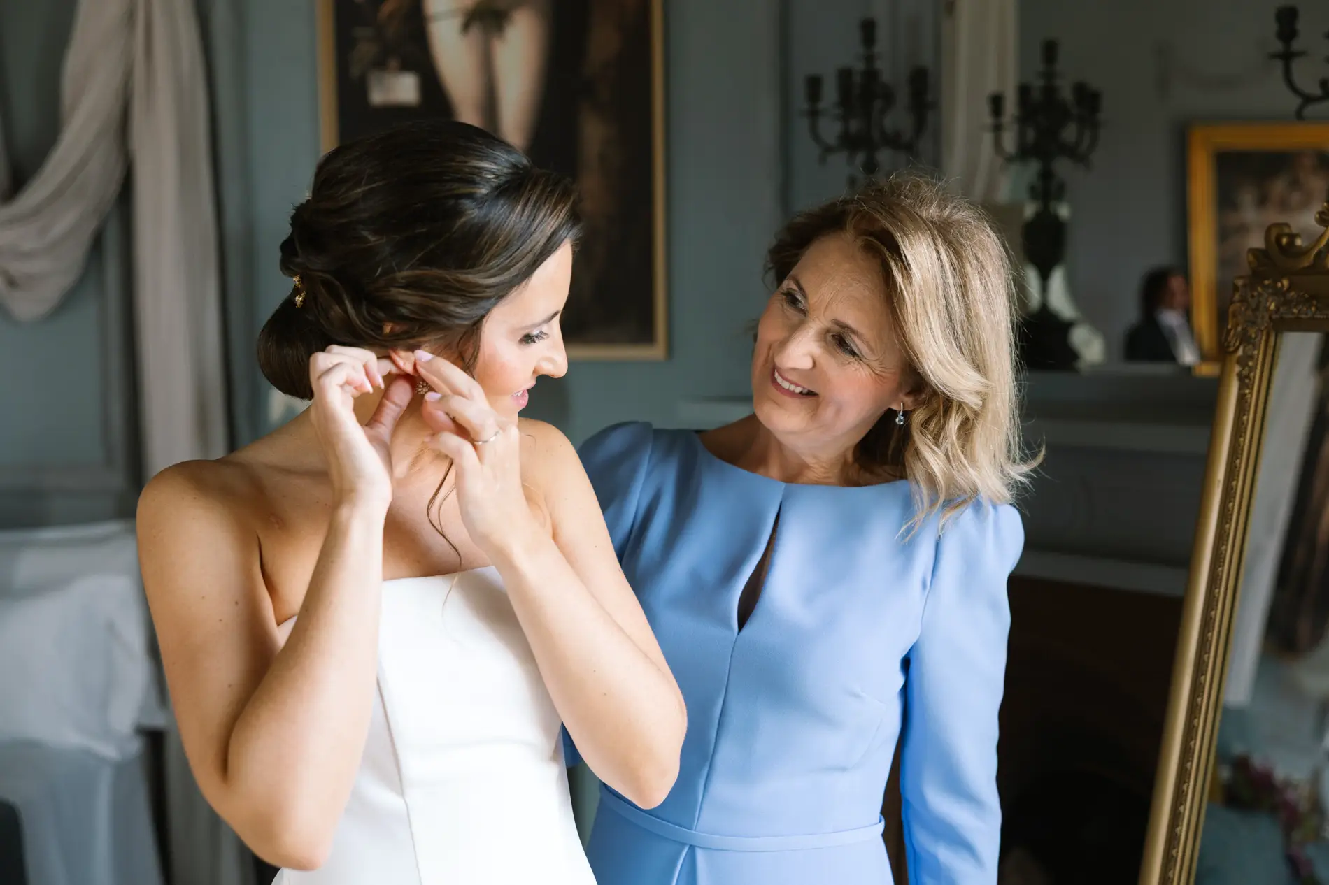 María se pone los pendientes junto a una familiar vestida de azul, en Casa Colorada, Badajoz