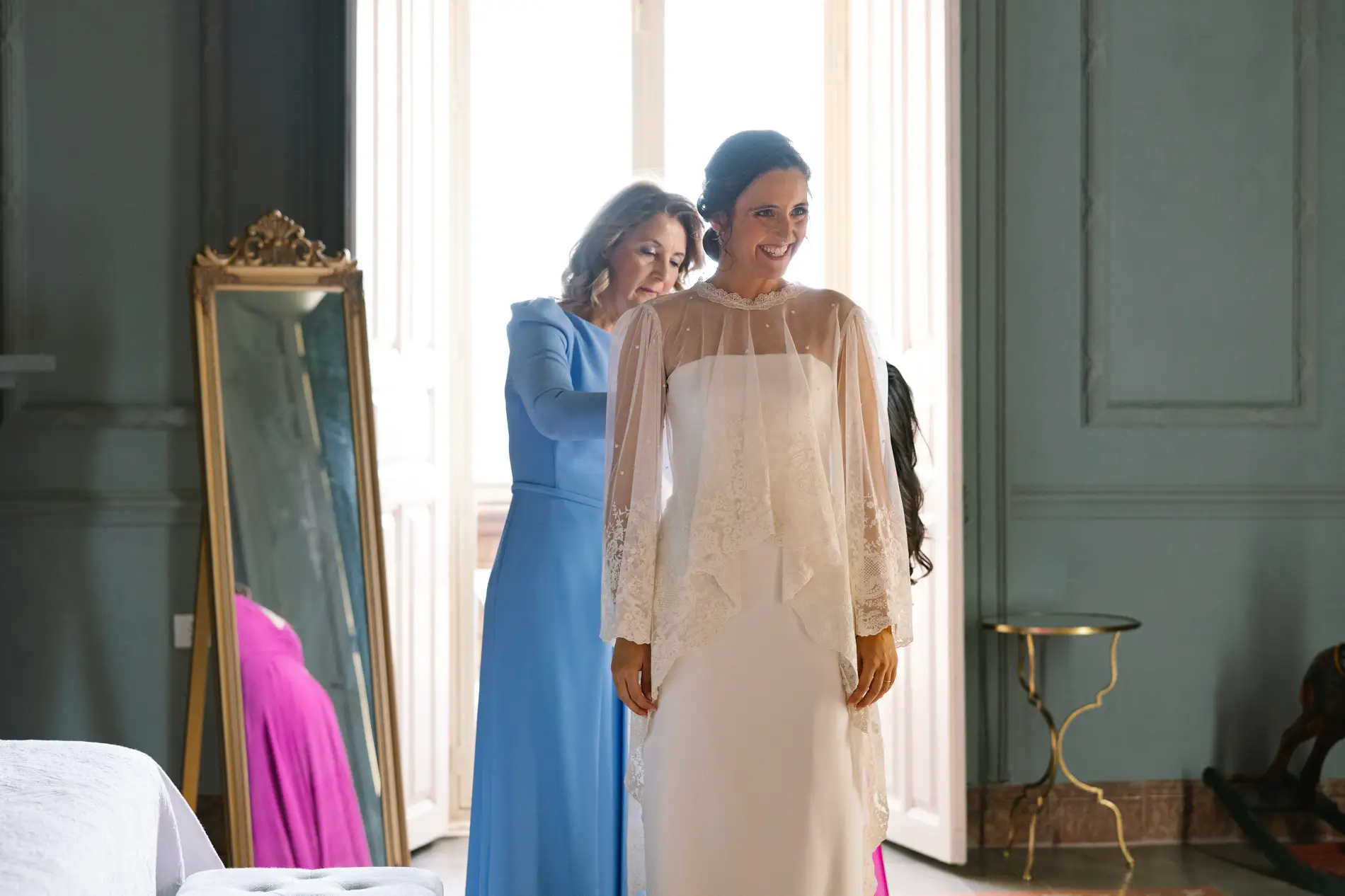 Una familiar ayuda a María con la capa del vestido de novia, en Casa Colorada, Badajoz