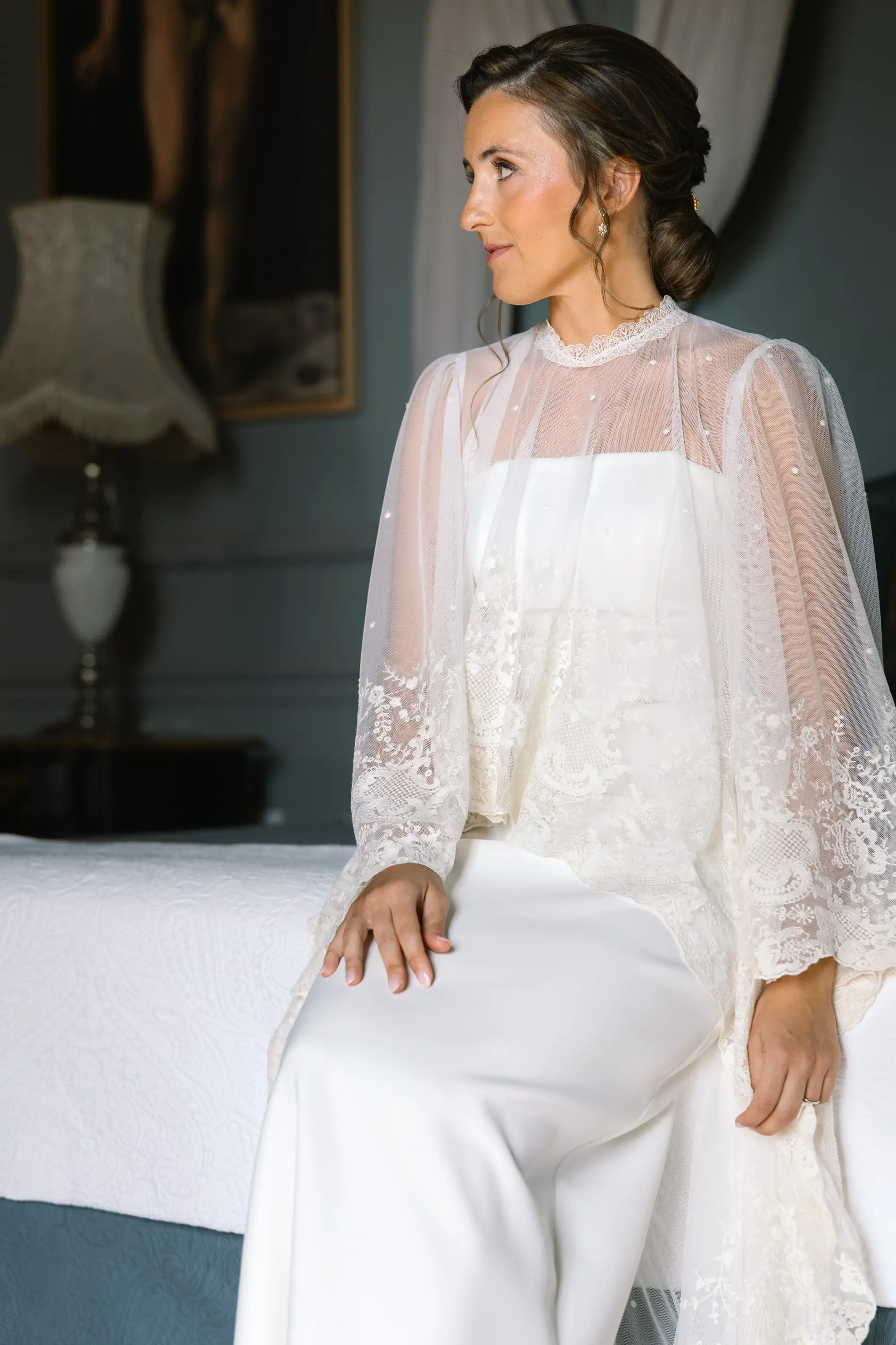 María sentada en la cama con su vestido y capa de tul bordado, en Casa Colorada, Badajoz