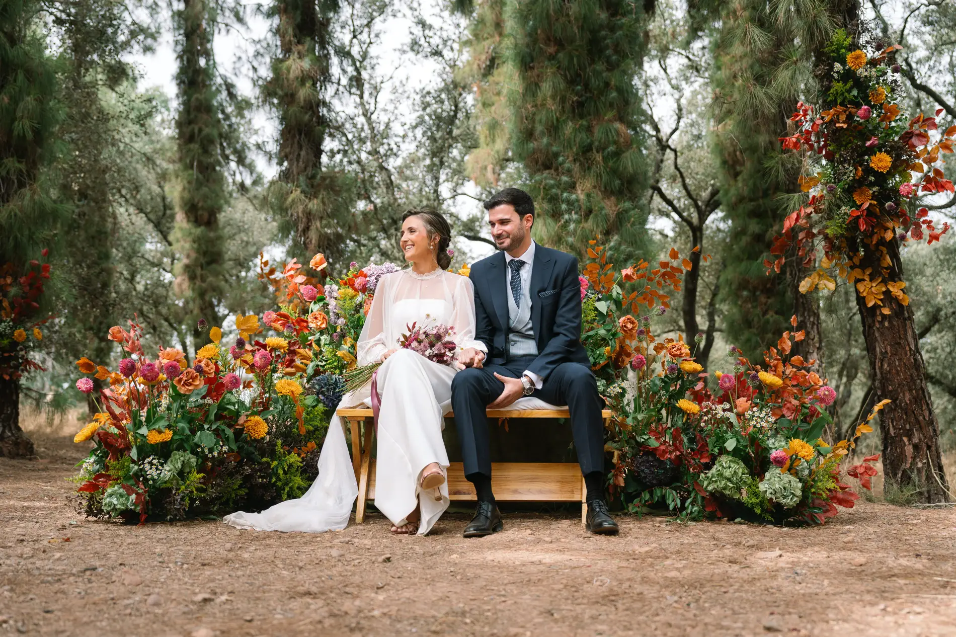 María y Álvaro sentados en el altar rodeado de flores de otoño, en Casa Colorada, Badajoz