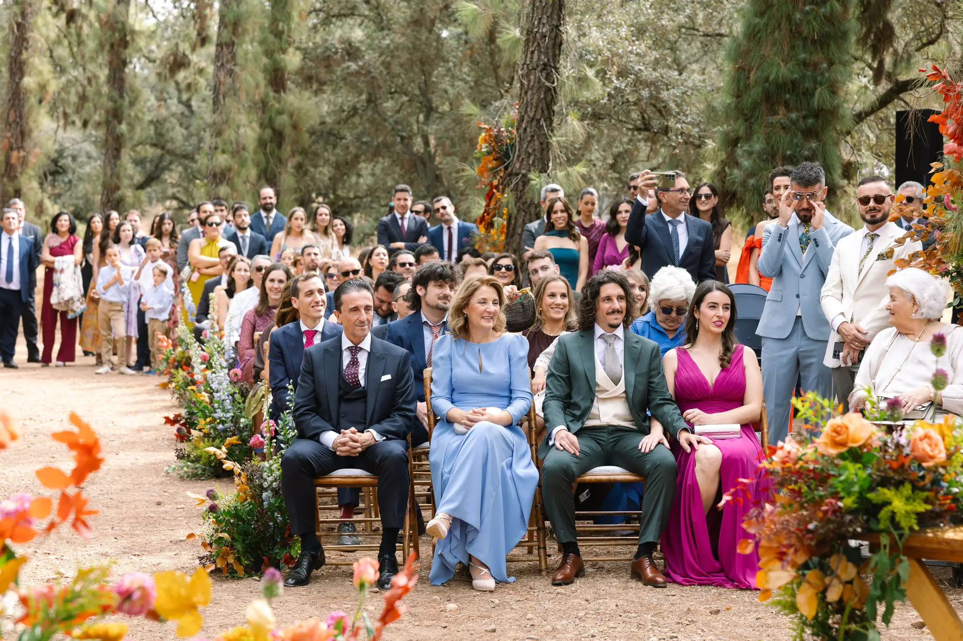 Invitados sentados en la ceremonia al aire libre entre los pinos, en Casa Colorada, Badajoz