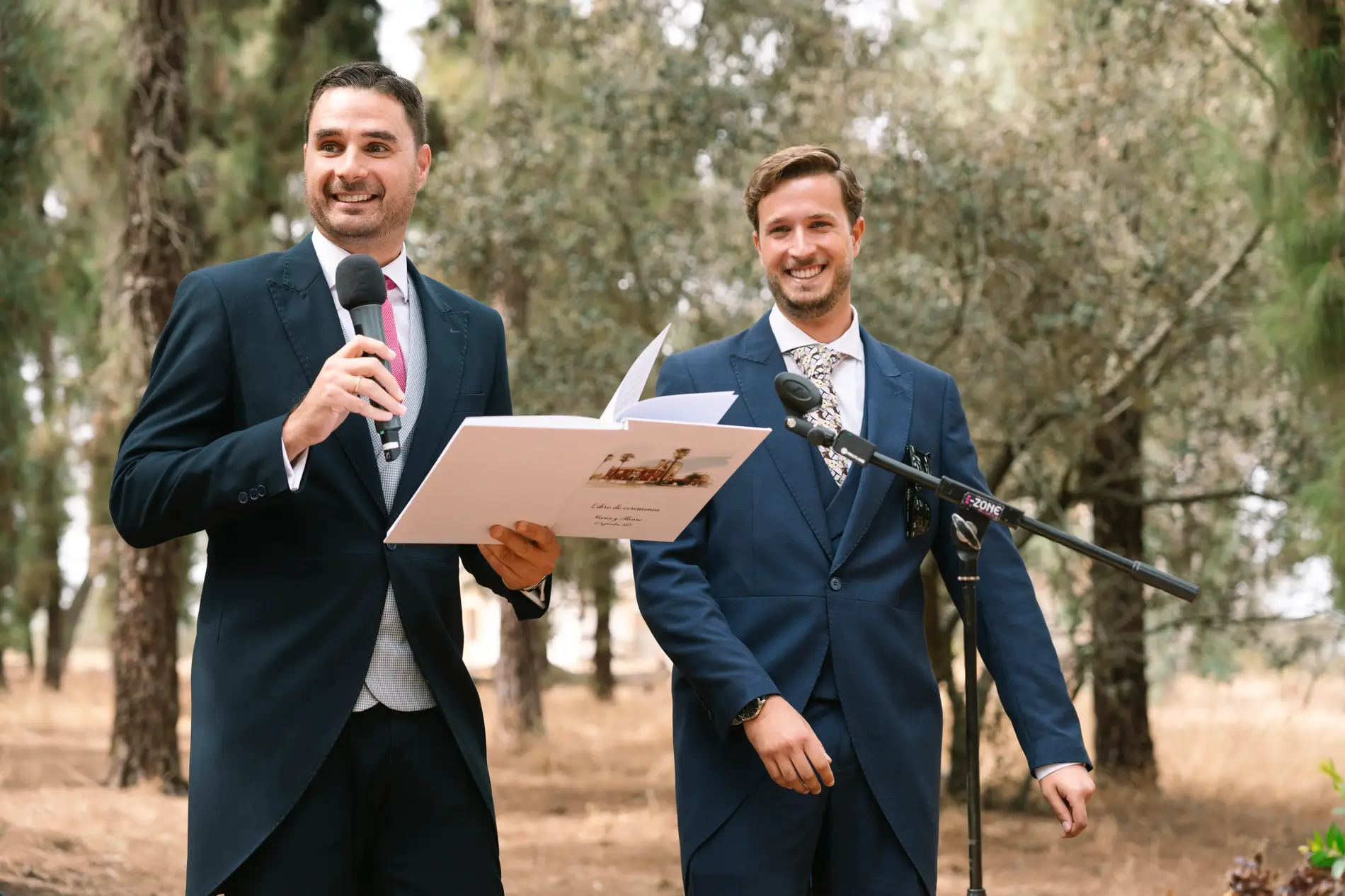 Dos amigos leen un texto con micrófono durante la ceremonia, en Casa Colorada, Badajoz