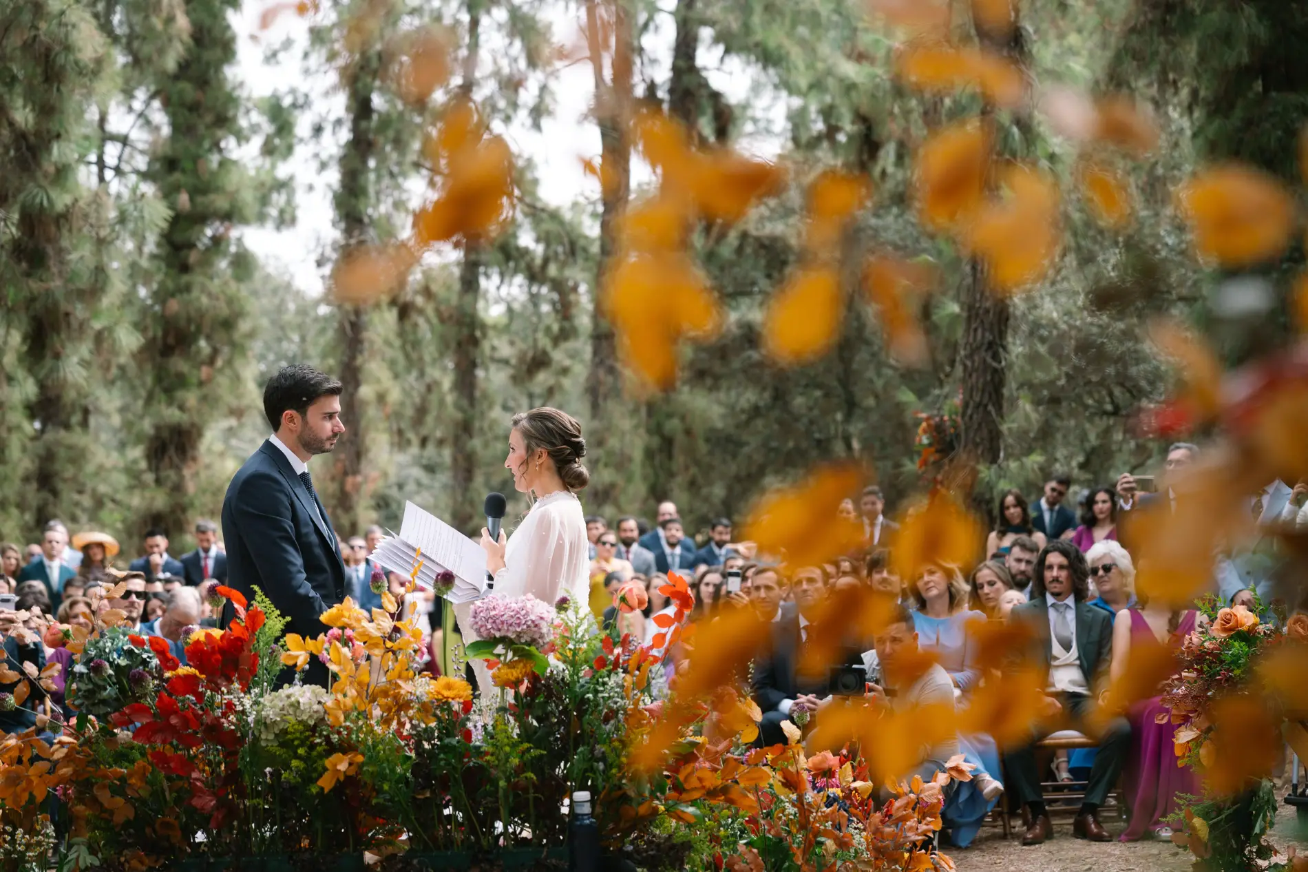 Ceremonia entre flores de otoño y pinos, vista entre hojas naranjas, en Casa Colorada, Badajoz