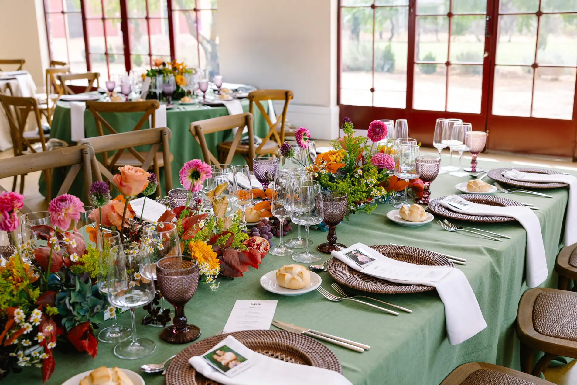 Mesa del banquete con mantel verde y flores de colores, en Casa Colorada, Badajoz
