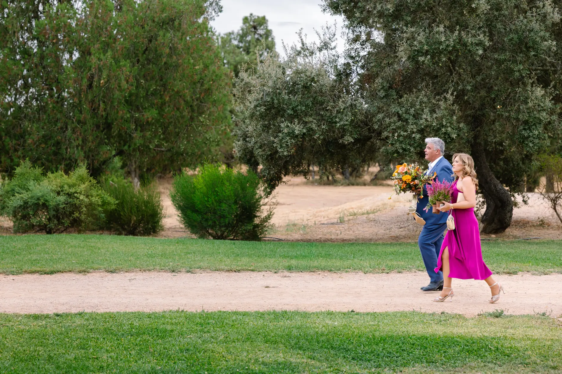 Una invitada cruza el jardín con flores hacia la fiesta, en Casa Colorada, Badajoz